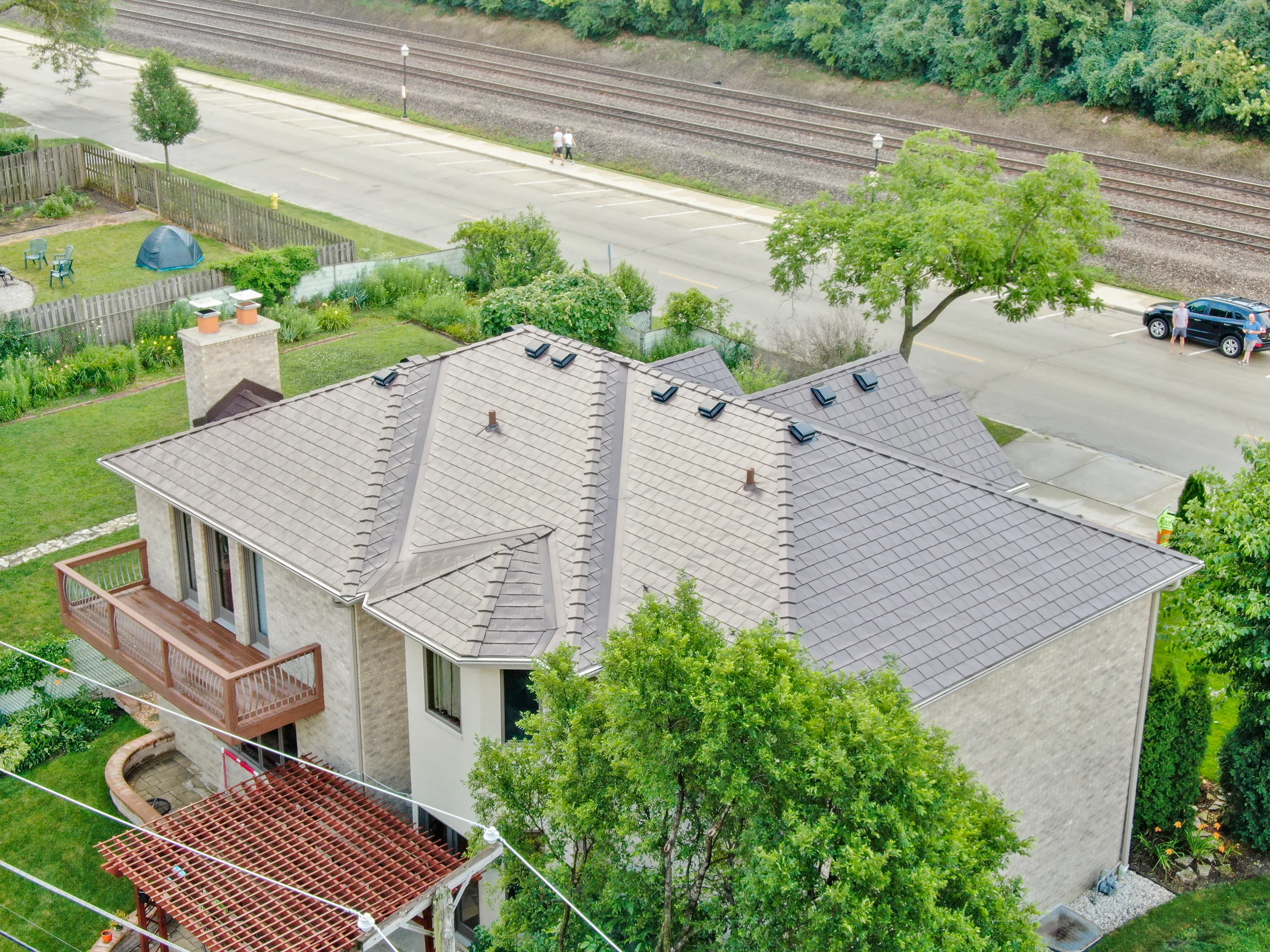 Colonial Brown Interlock Slate aluminum roof on a Colonial style home in a wooded area with lush greenery, Calredon Hills, Illinois