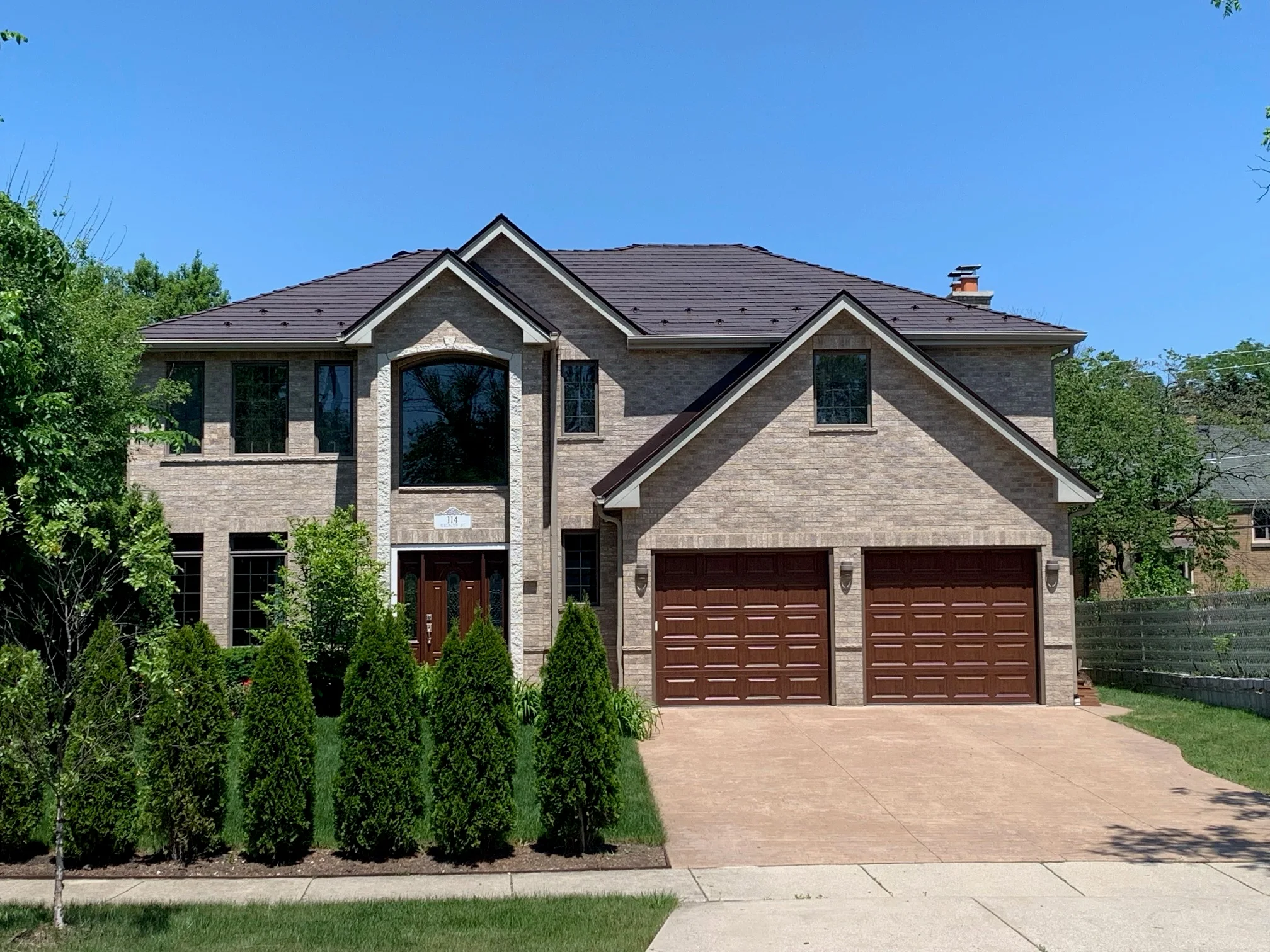 Colonial Brown Interlock Slate aluminum roof on a brown two-storey home with dormers among tall pines, Calredon Hills, Illinois