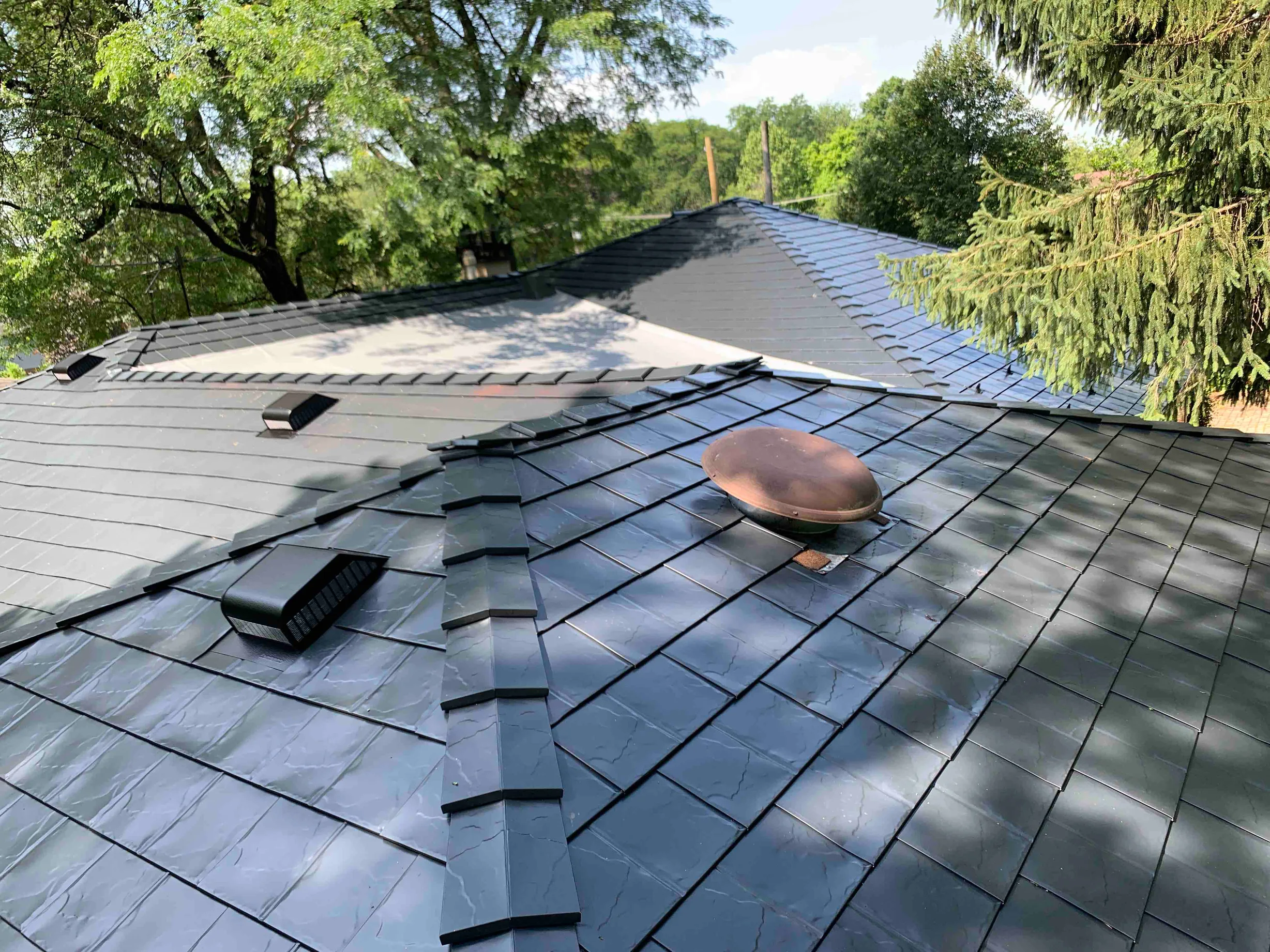 Black Interlock Slate aluminum roof on a black two-storey home with dormers among tall trees in a, Lombard, Illinois