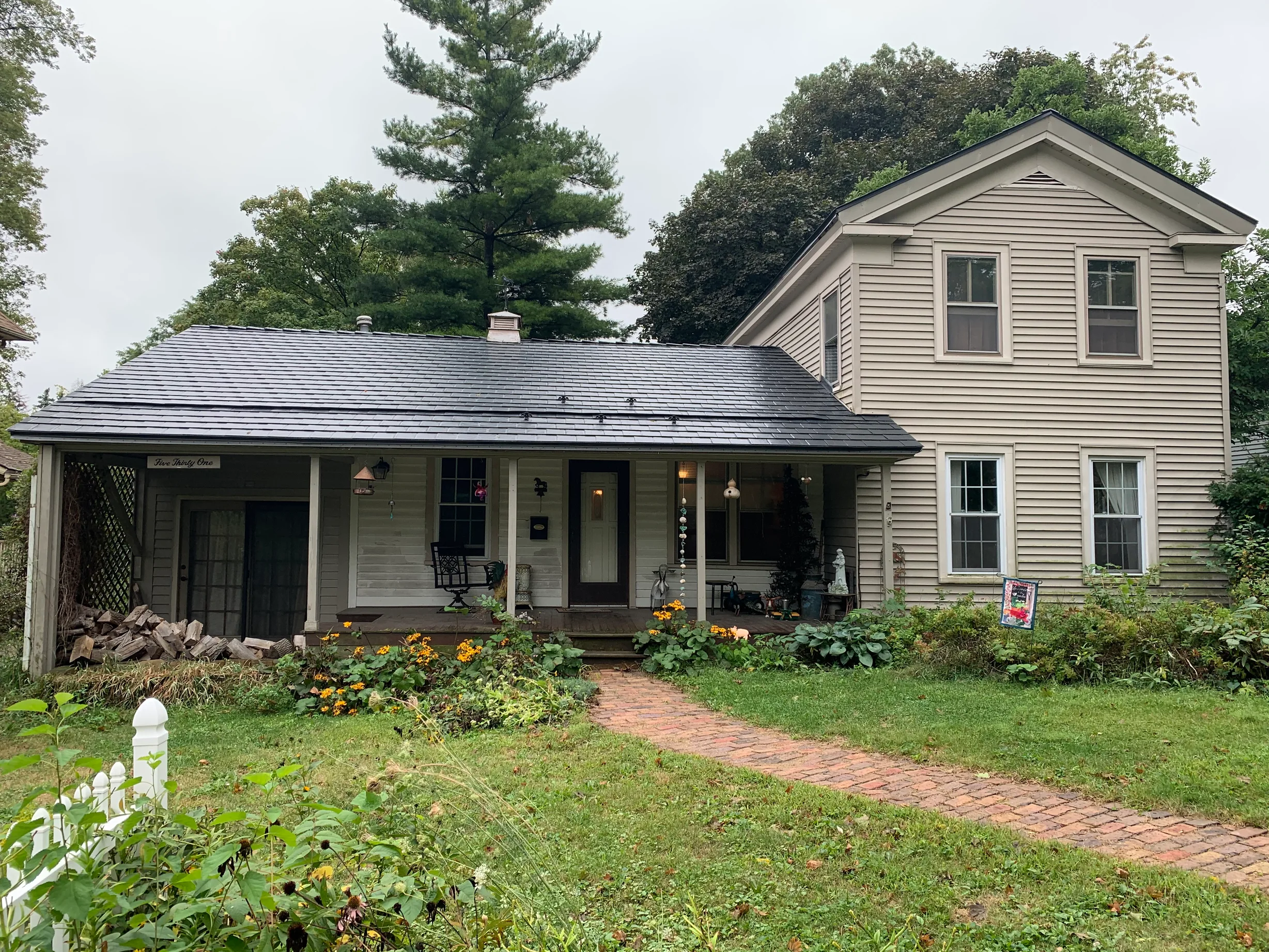 Black Interlock Slate aluminum roof on a tan two-storey farmhouse with a covered front porch among, Woodstock, Illinois