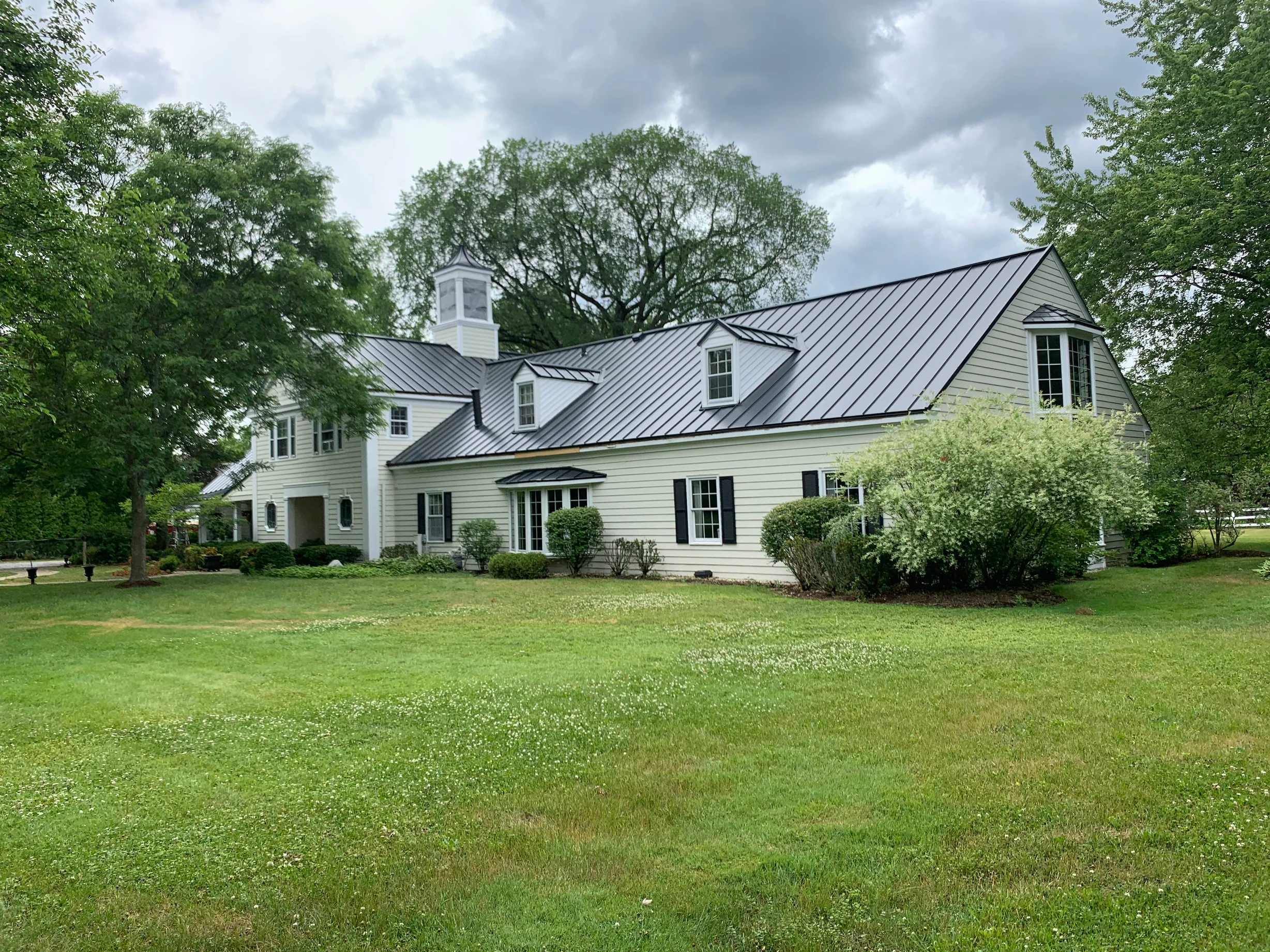 Black Interlock Standing Seam aluminum roof on a Colonial home with a metal roof and dormers among tall, Lake Forest, Illinois