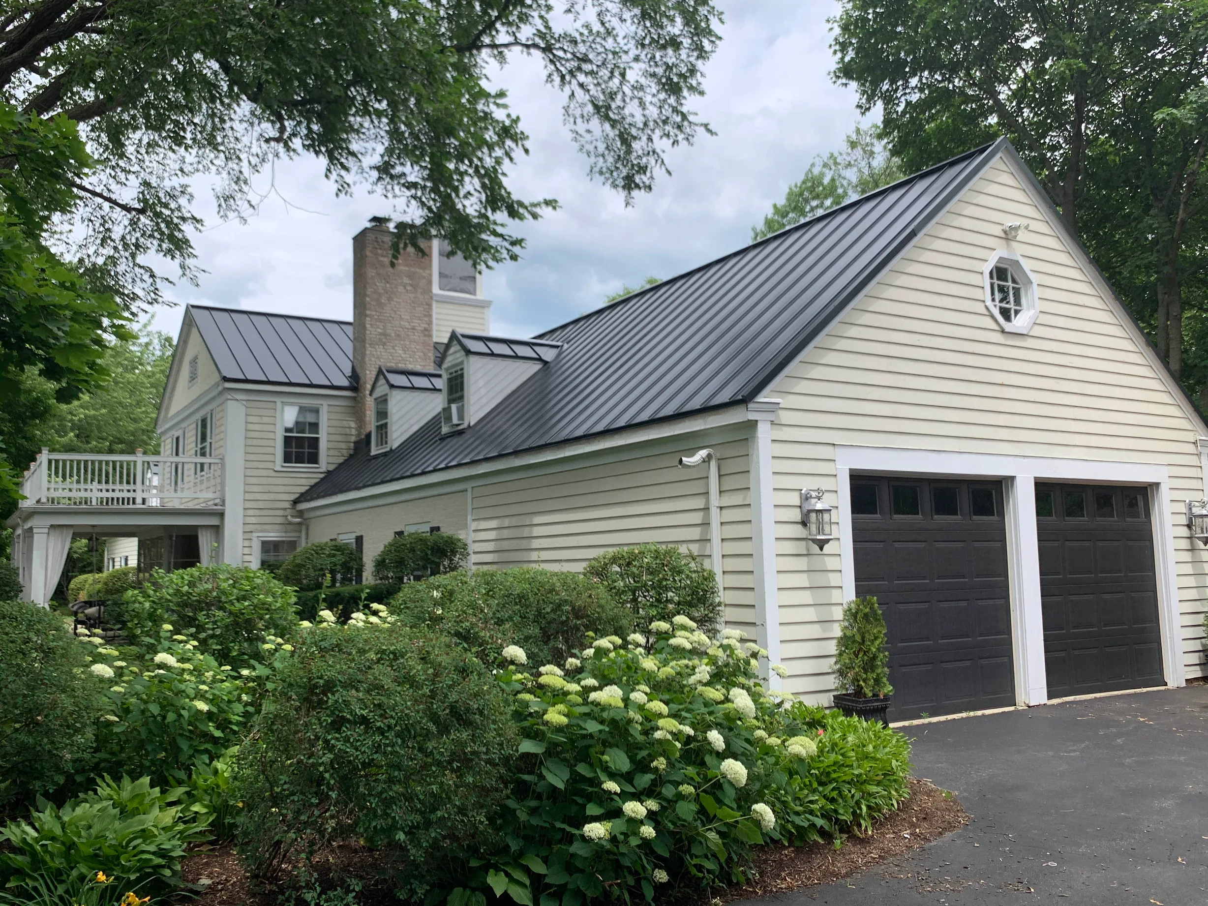 Black Interlock Standing Seam aluminum roof on a cream-coloured two-storey colonial home with a metal roof, Lake Forest, Illinois