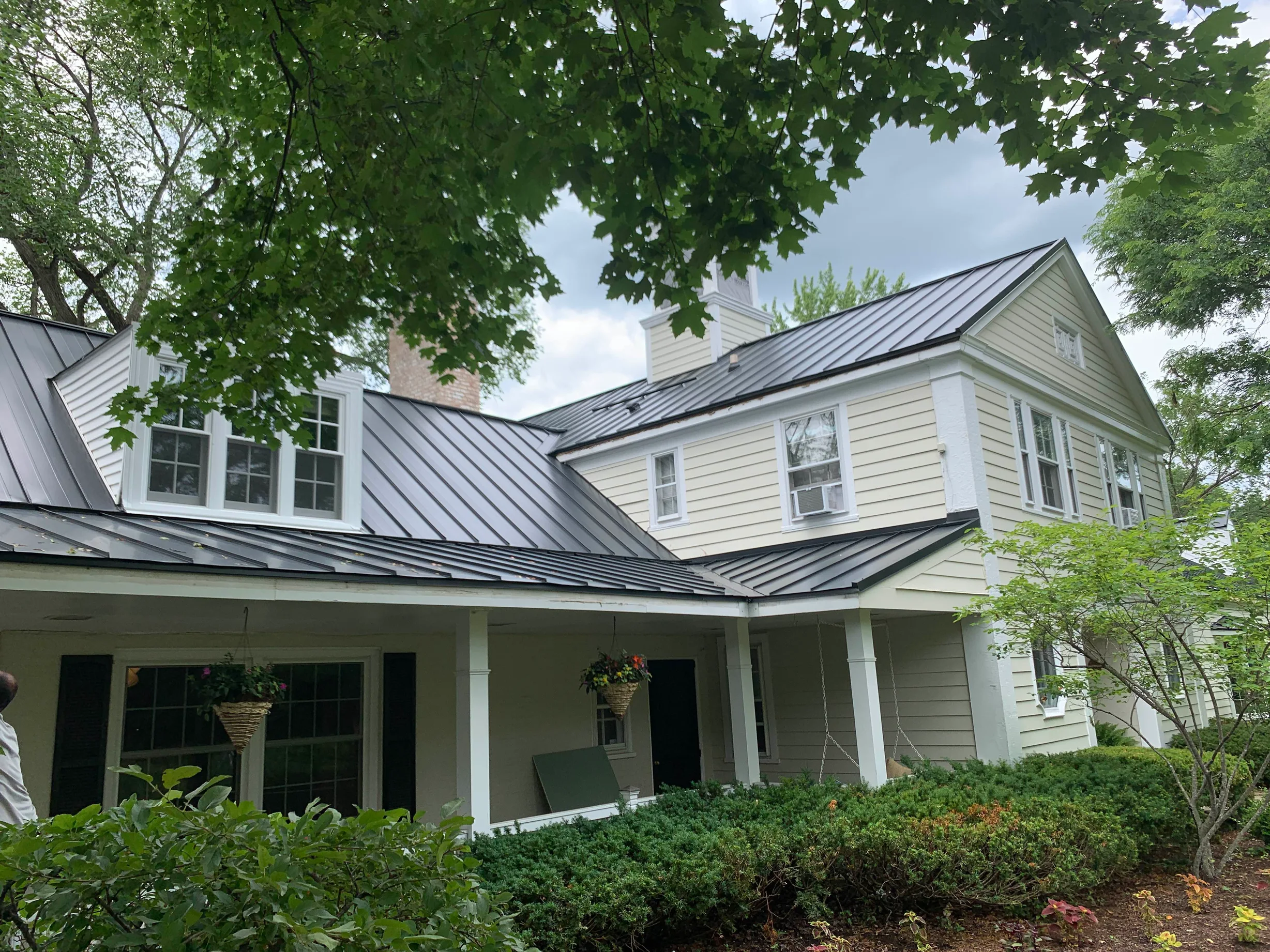 Black Interlock Standing Seam aluminum roof on a cream two-storey Colonial with dormers in a forested, Lake Forest, Illinois