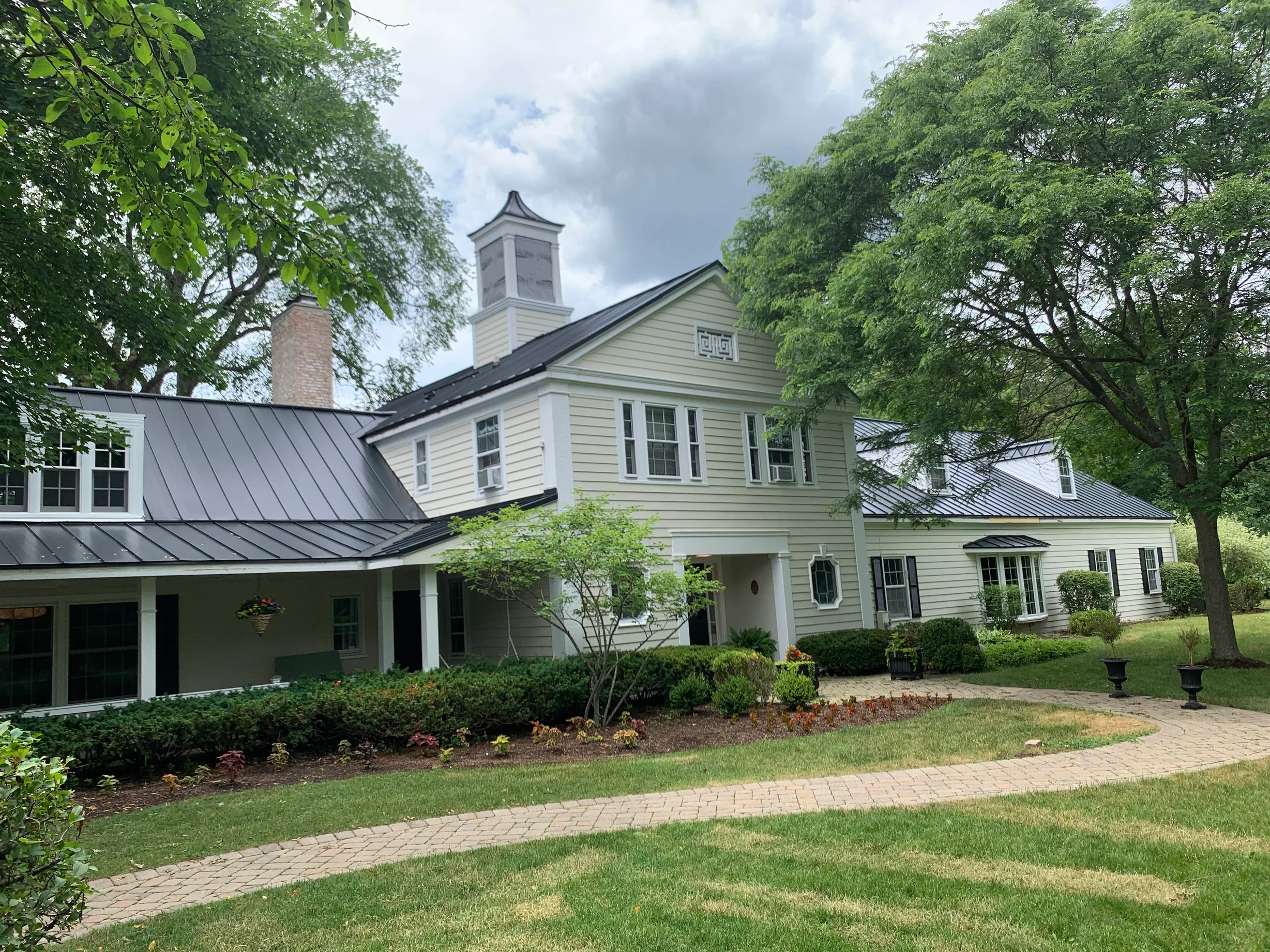 Black Interlock Standing Seam aluminum roof on a two-storey Colonial home with dormers in a forested, Lake Forest, Illinois