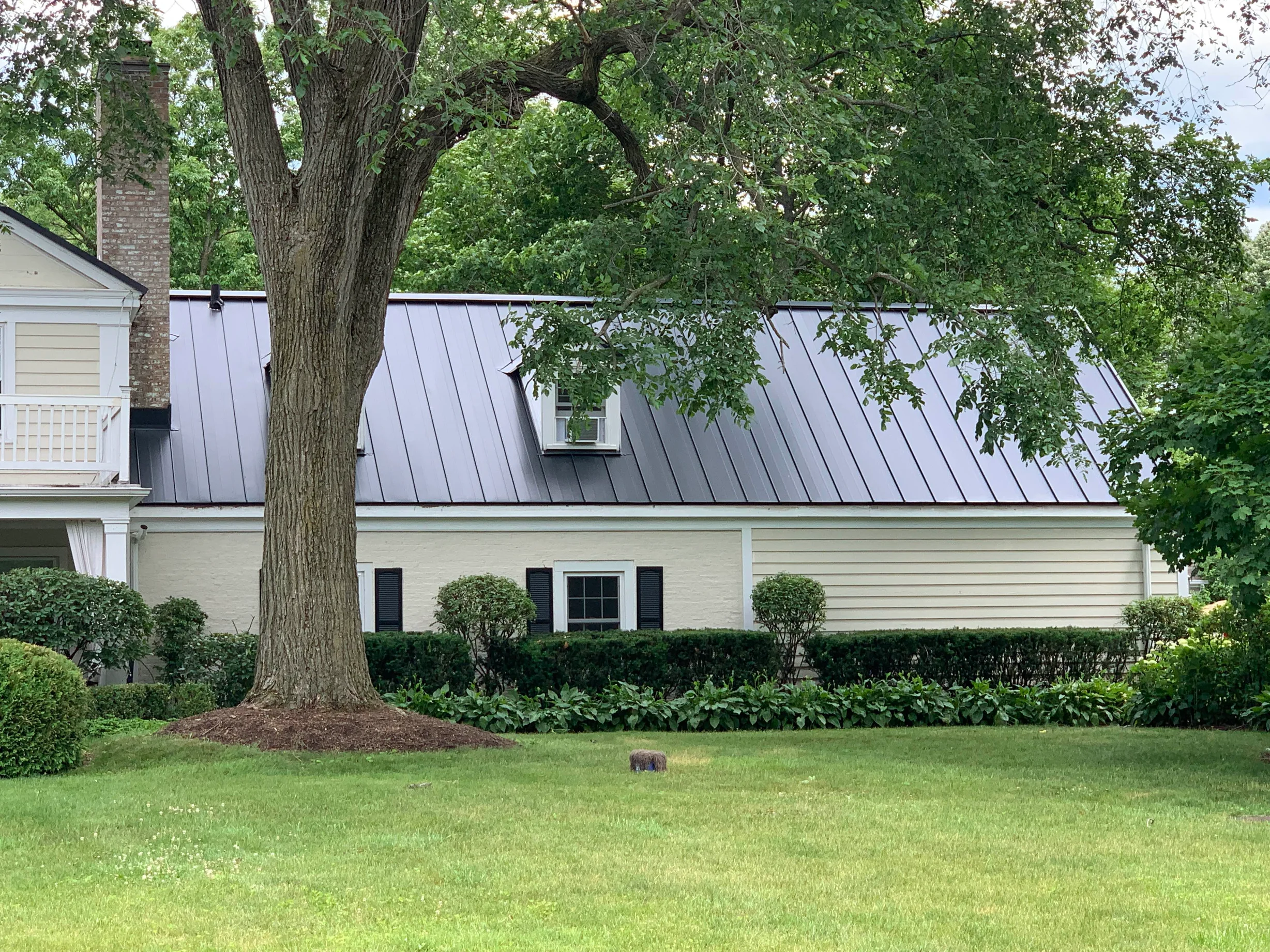 Black Interlock Standing Seam aluminum roof on a cream-coloured colonial home with a metal roof in a, Lake Forest, Illinois