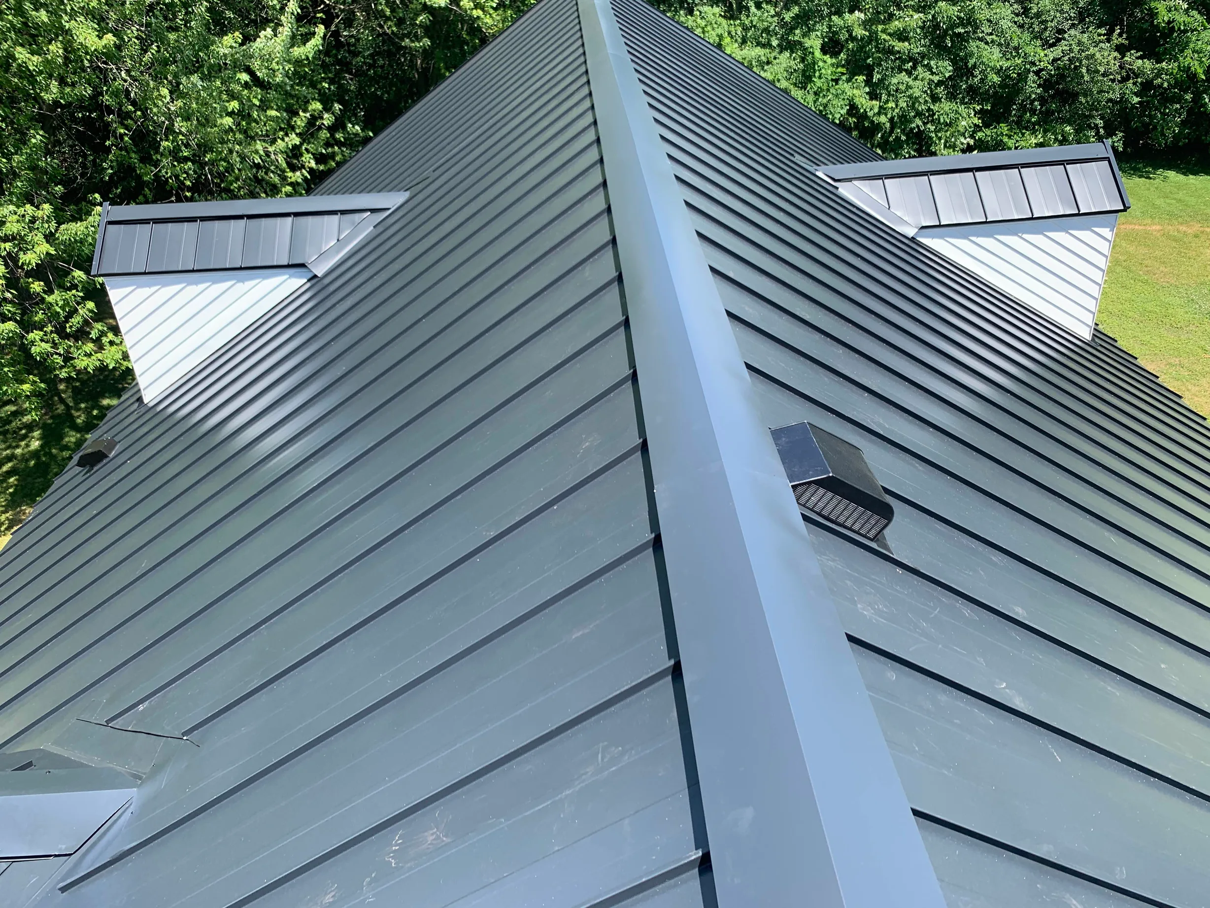 Black Interlock Standing Seam aluminum roof on a green metal roof on a single-family home in a forested, Lake Forest, Illinois