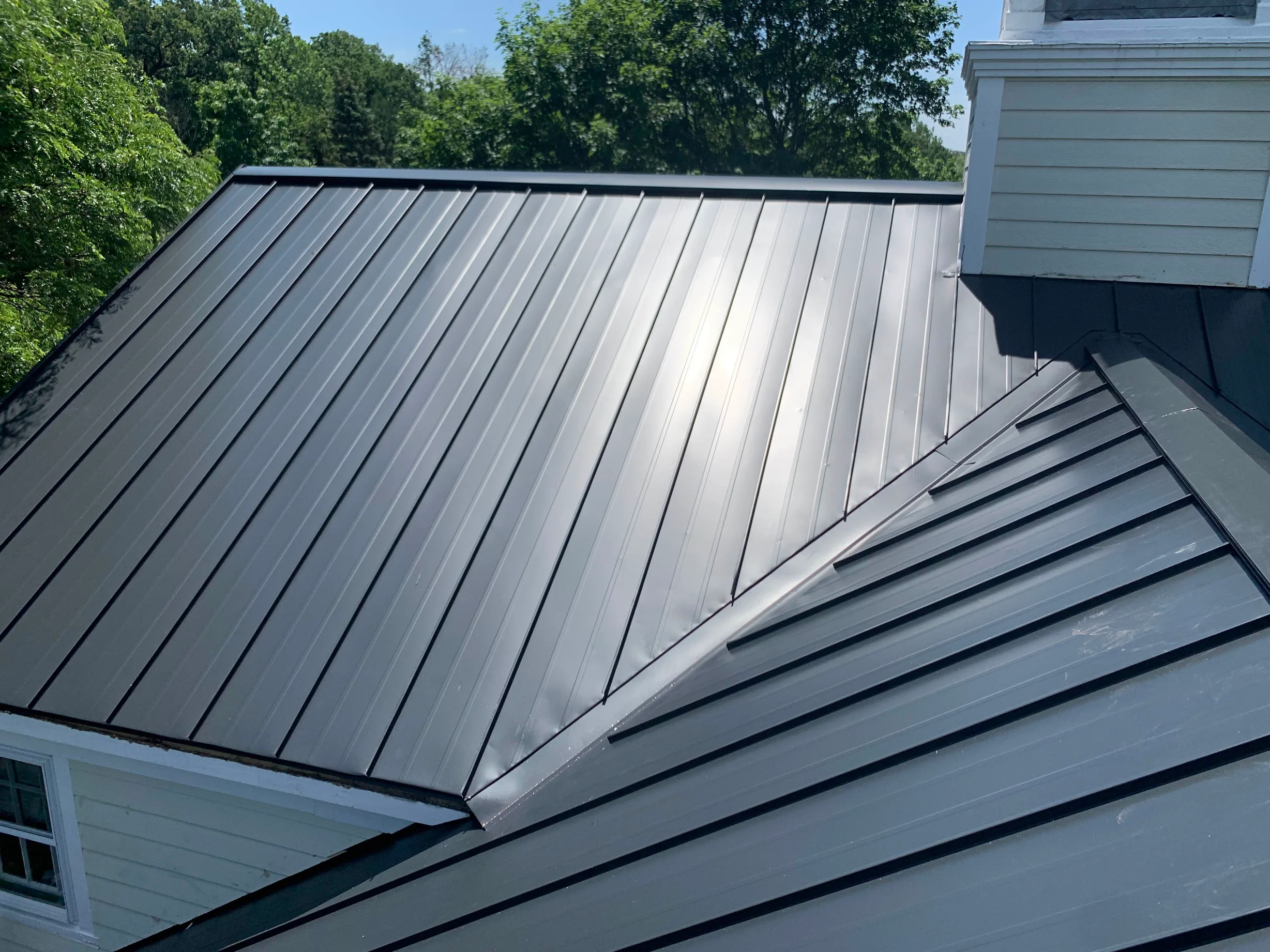 Black Interlock Standing Seam aluminum roof on a black single-family home with a metal roof among tall, Lake Forest, Illinois