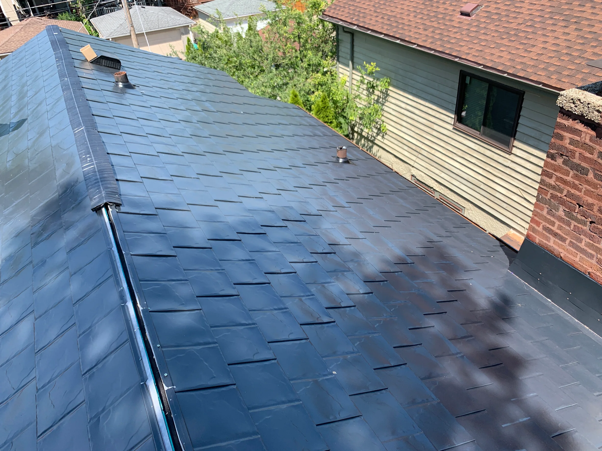 Black Interlock Slate aluminum roof on a two-storey home with brick and vinyl siding in a suburban, Oak Park, Illinois