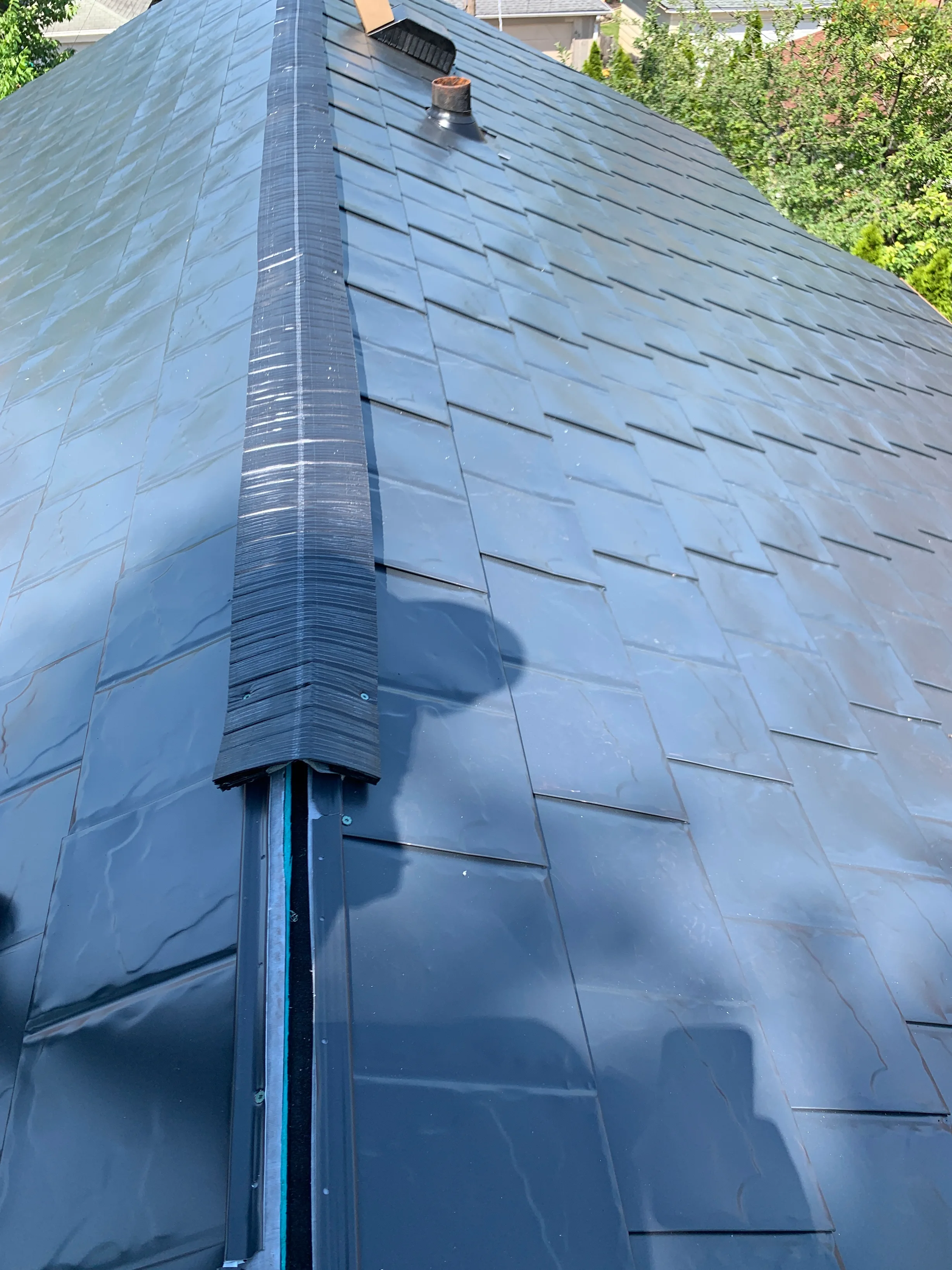 Black Interlock Slate aluminum roof being installed on a single-family home in a forested suburban setting, Oak Park, Illinois