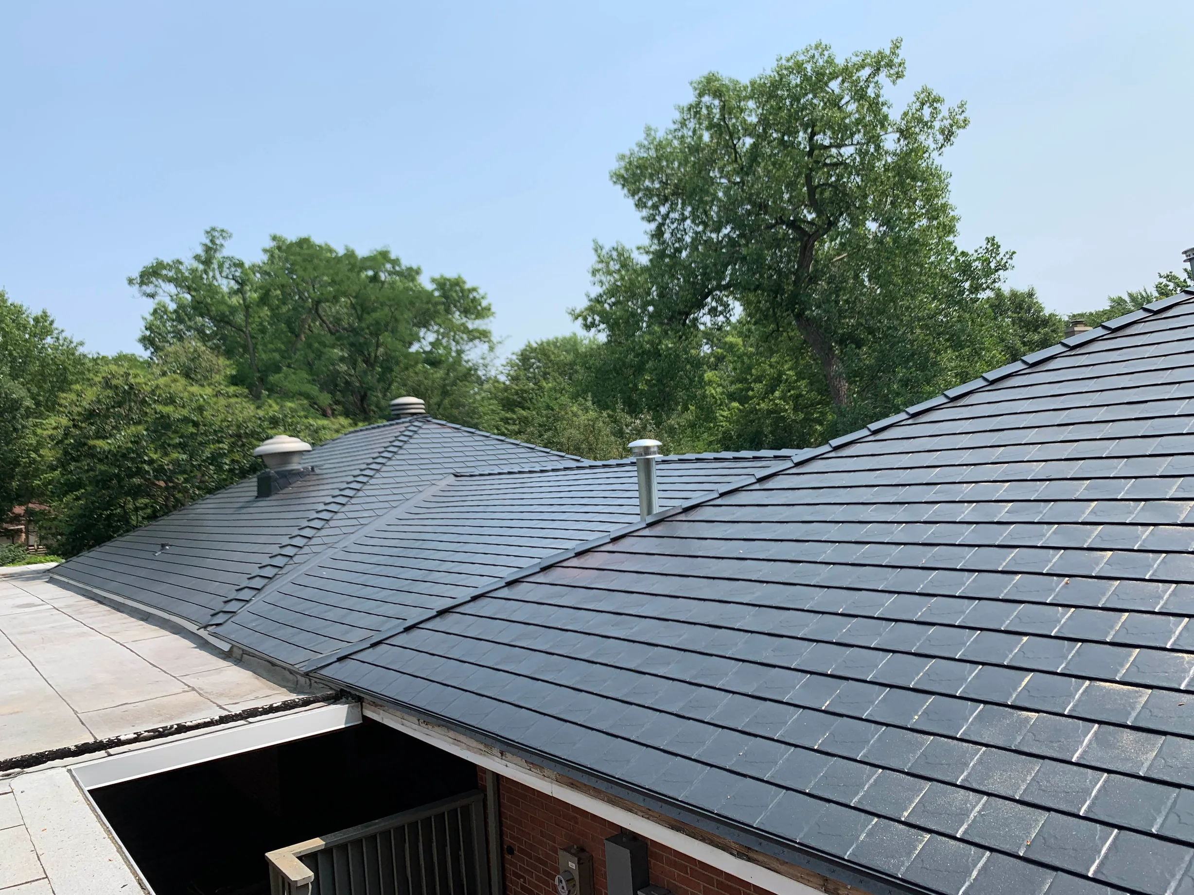Black Interlock Slate aluminum roof on a red brick house with metal roof in a forested suburb, Flossmoor, Illinois