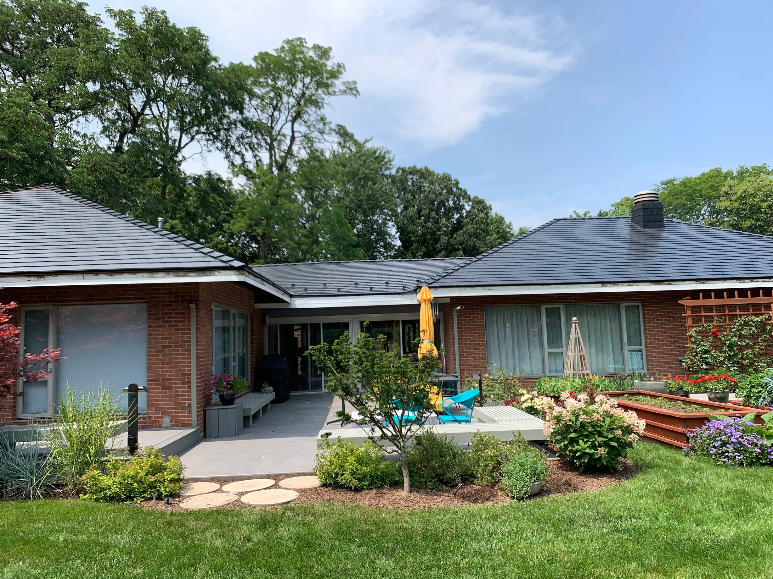 Black Interlock Slate aluminum roof on a red brick ranch home with a black metal roof among tall, Flossmoor, Illinois