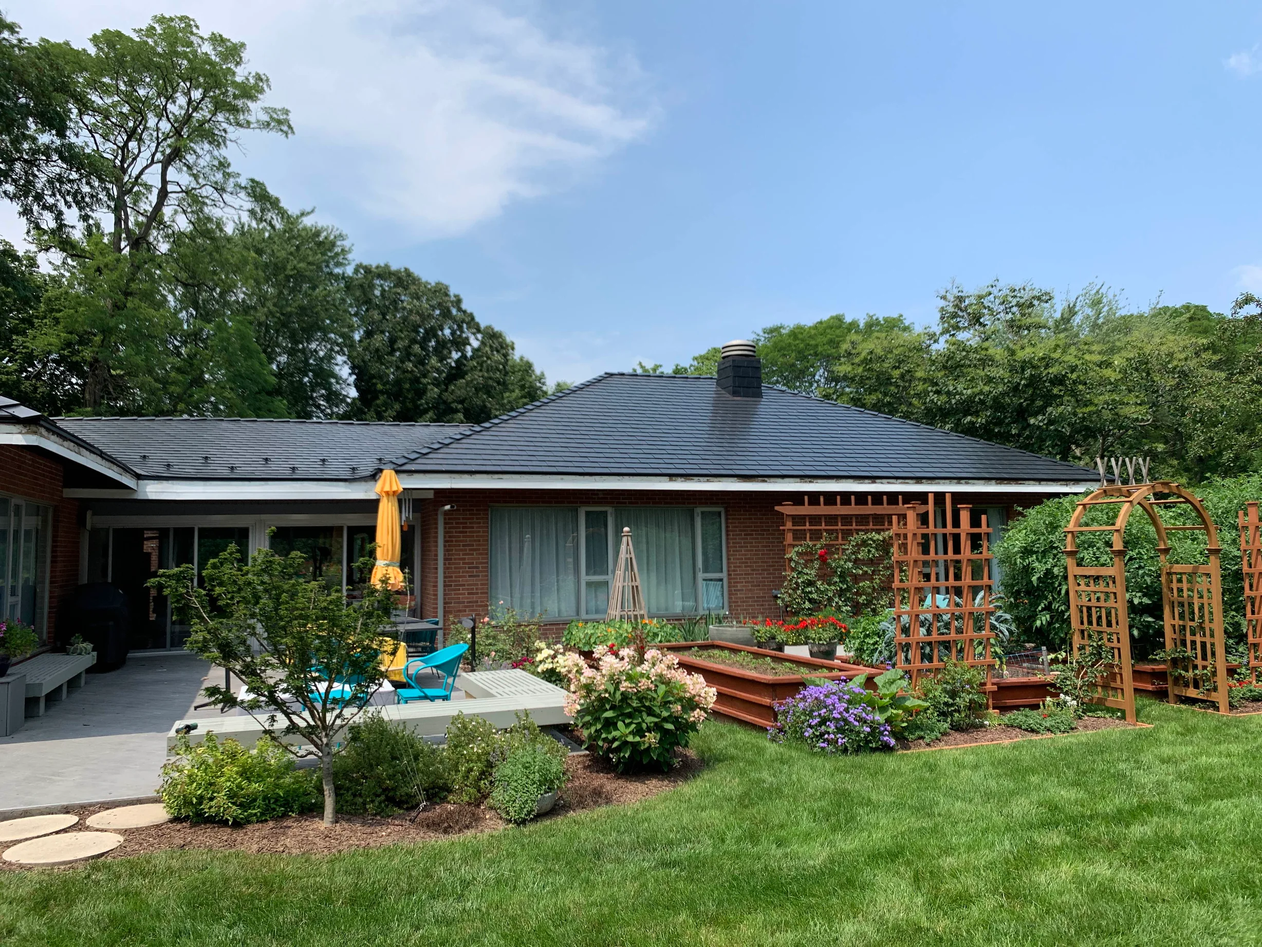 Black Interlock Slate aluminum roof on a red brick ranch home with a large front yard among trees, Flossmoor, Illinois