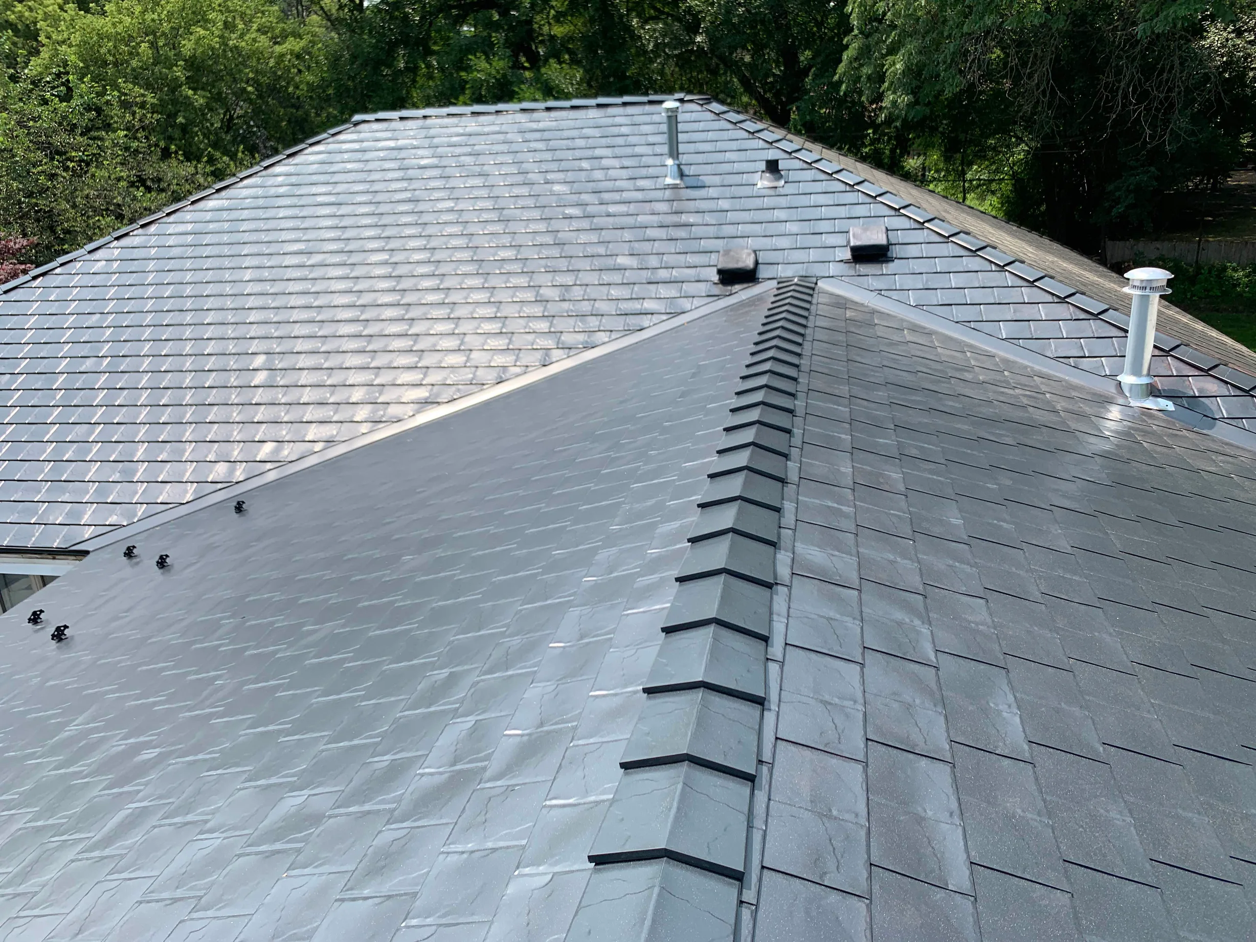 Black Interlock Slate aluminum roof on a black two-storey home with dormers in a wooded area, Flossmoor, Illinois