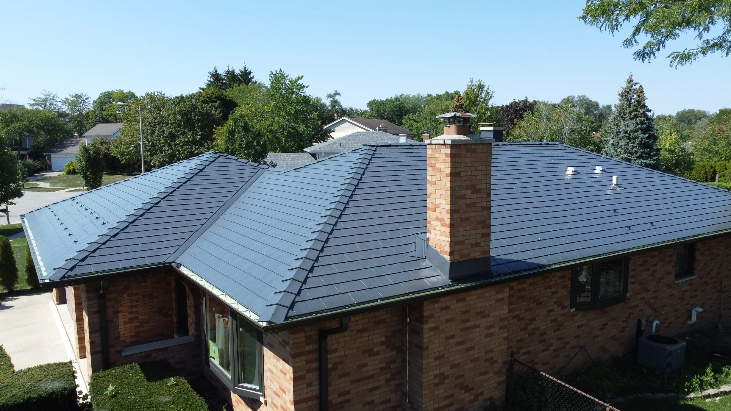 Deep Charcoal Interlock Slate aluminum roof on a red brick ranch home with a metal roof in a suburban, Westmont, Illinois