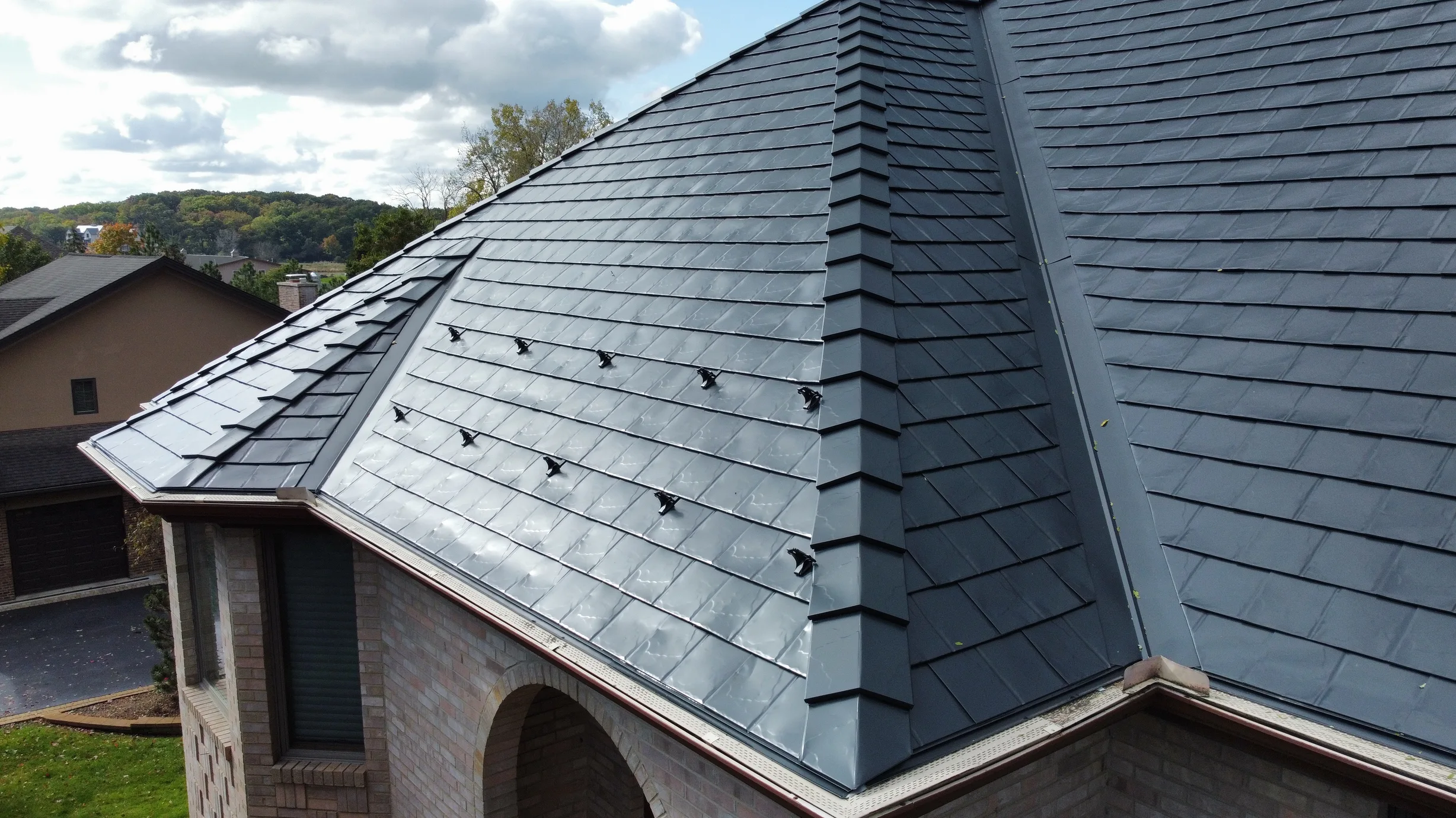 Black Interlock Slate aluminum roof on a brown one-storey home with a metal roof among green trees, Lemont, Illinois