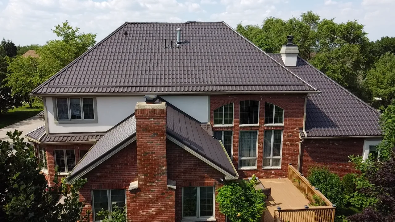 Tudor Brown Interlock Tile aluminum roof on a Tudor style single-family home in a suburban forested, Lemont, Illinois