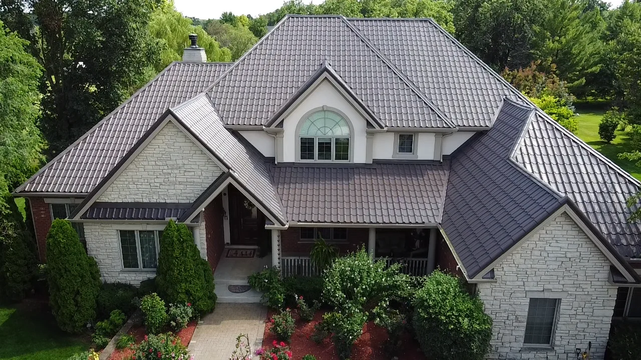 Tudor Brown Interlock Tile aluminum roof on a white single-family Tudor home in a forested suburban, Lemont, Illinois