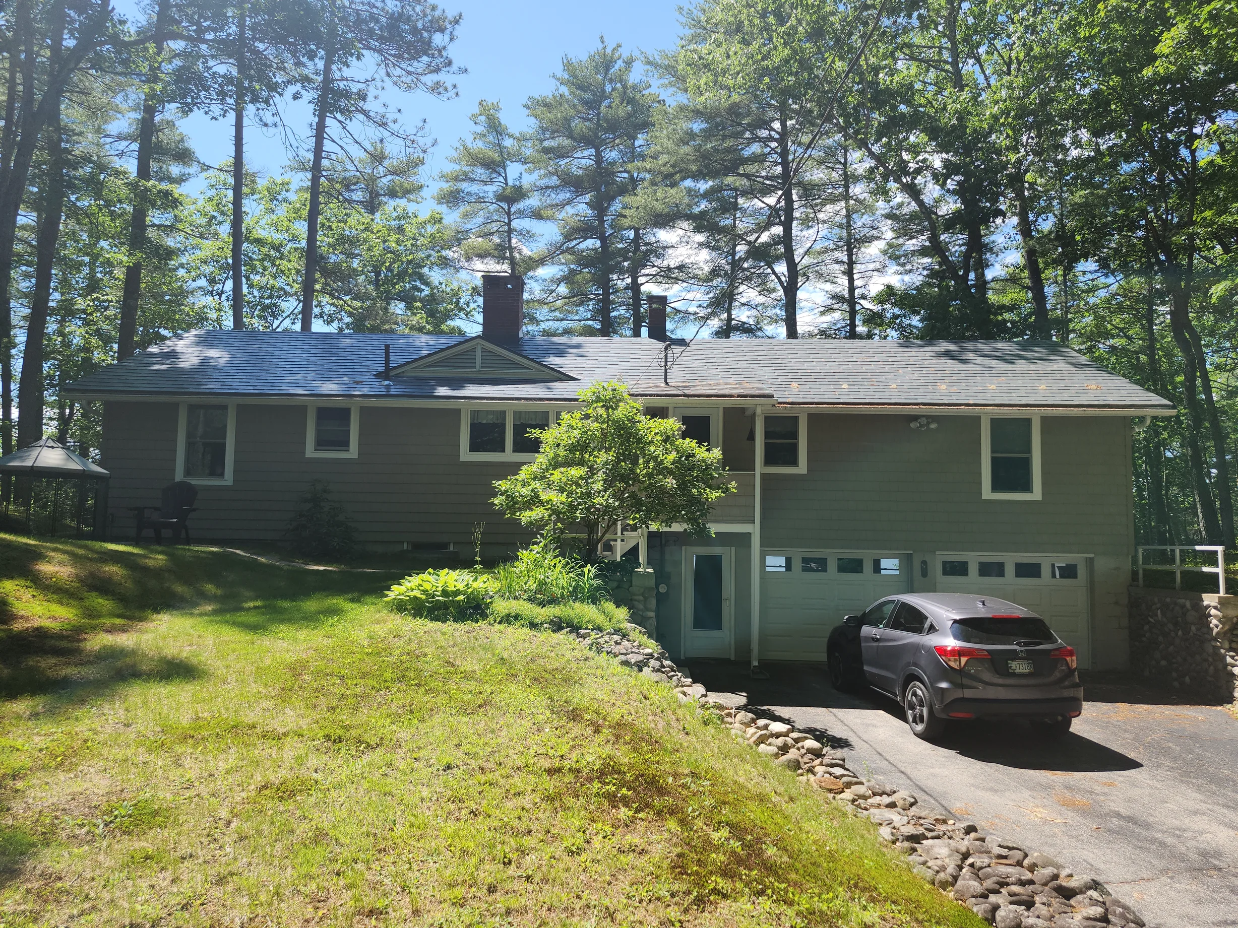 Charcoal Grey Interlock Shingle aluminum roof on a grey ranch style home with a metal roof in a wooded area, New Gloucester, Maine