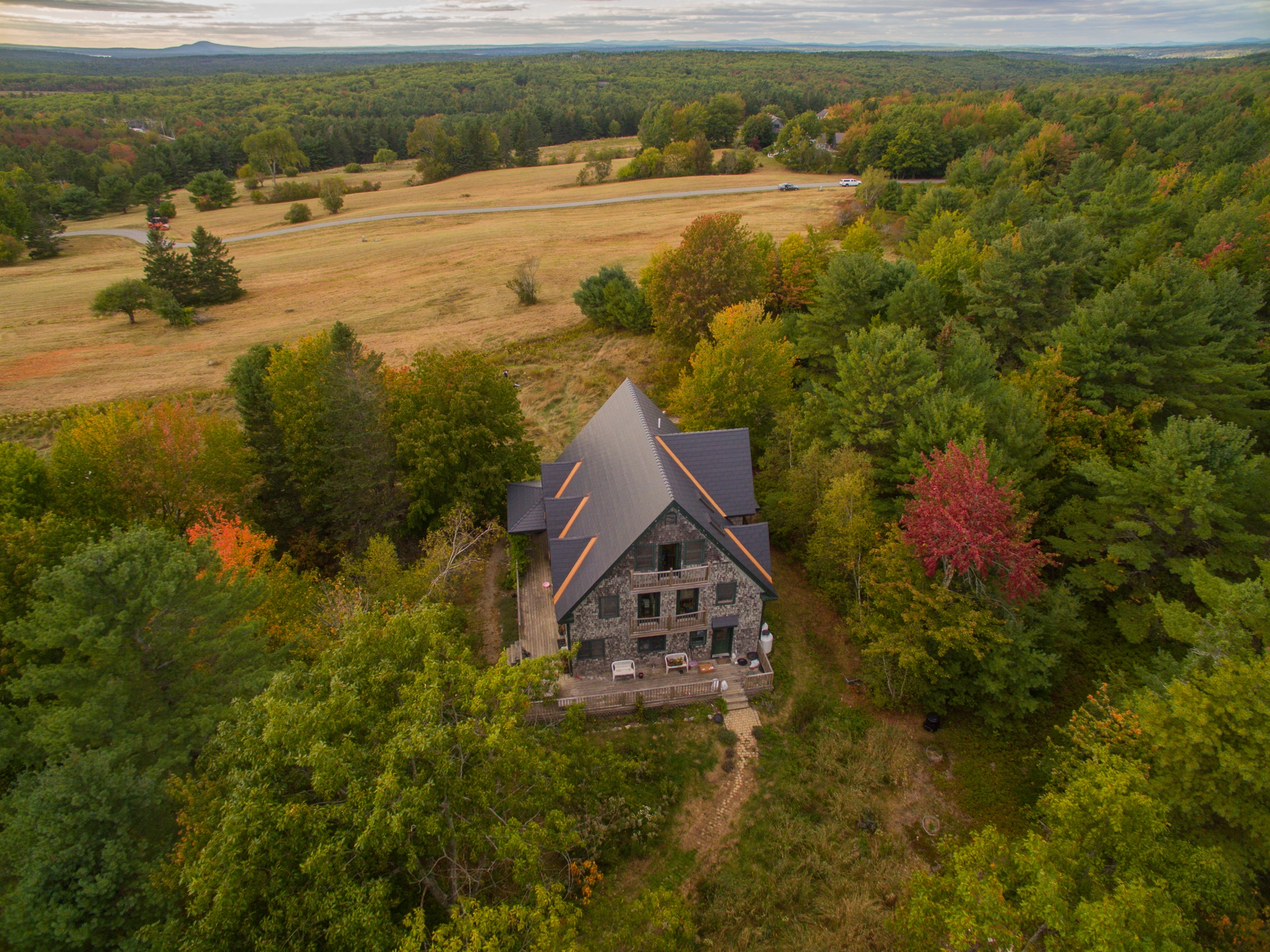 Deep Charcoal Interlock Cedar Shingle aluminum roof on a two-storey cottage with a grey metal roof in a wooded area, Bar Harbor, Maine