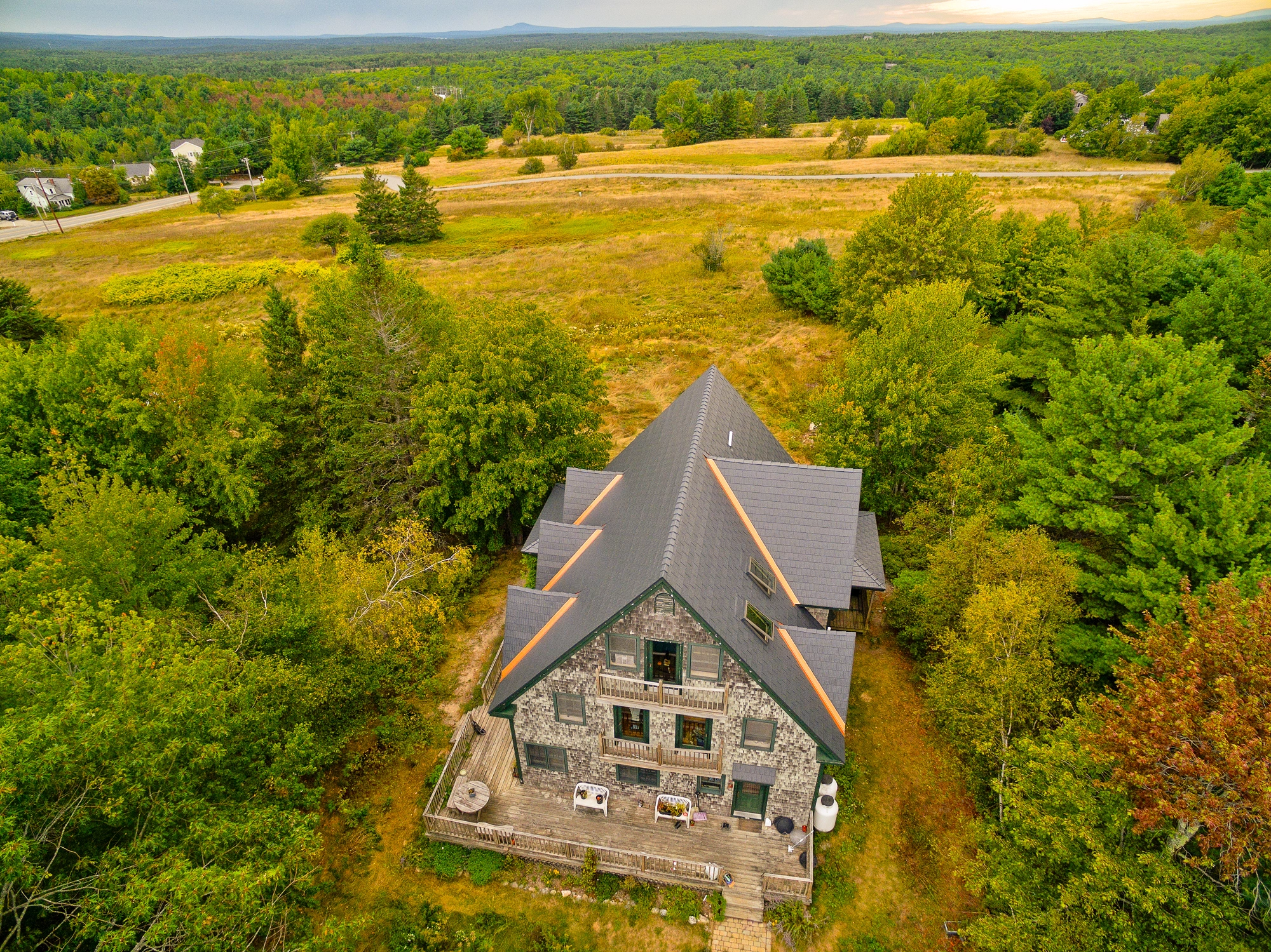 Deep Charcoal Interlock Cedar Shingle aluminum roof on a two-storey Cape Cod home with dormers among tall trees, Bar Harbor, Maine