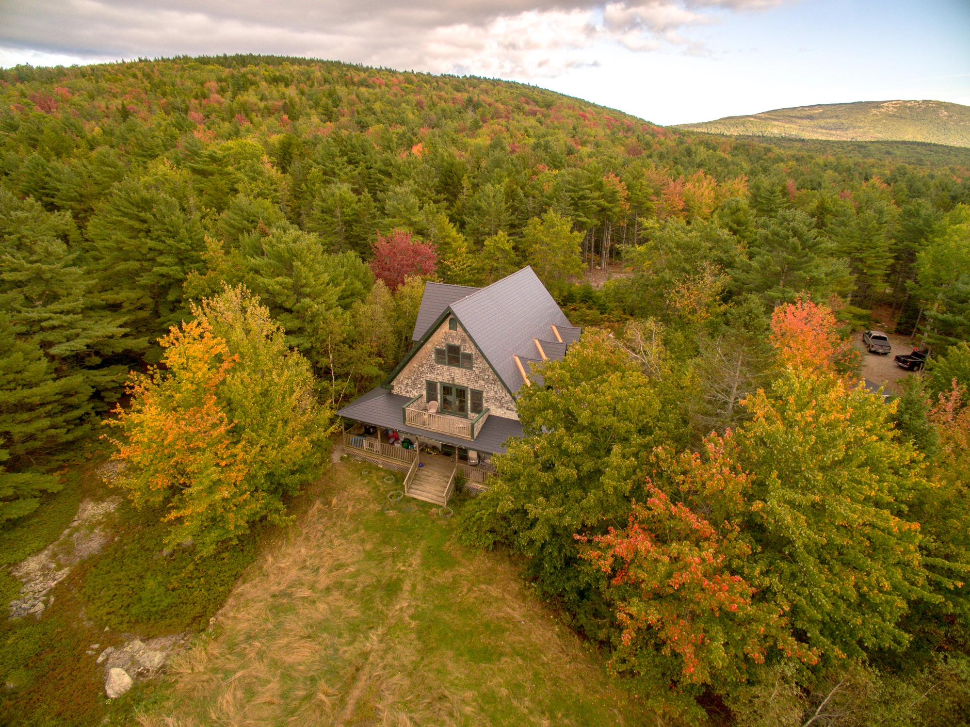 Deep Charcoal Interlock Cedar Shingle aluminum roof on a two-storey Cape Cod home with dormers among tall trees, Bar Harbor, Maine