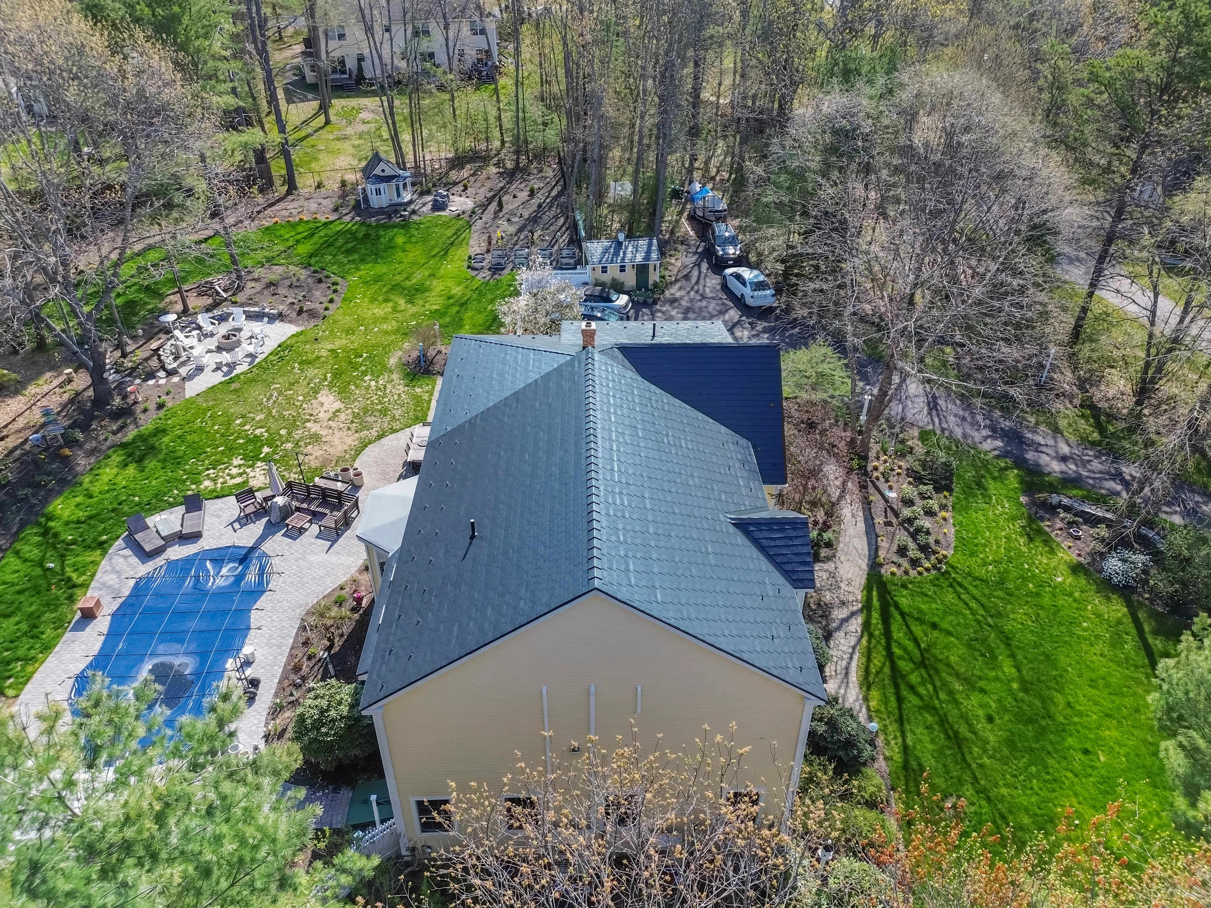 Black Interlock Slate aluminum roof on a two-storey home with a slate grey metal roof among tall, Brunswick, Maine