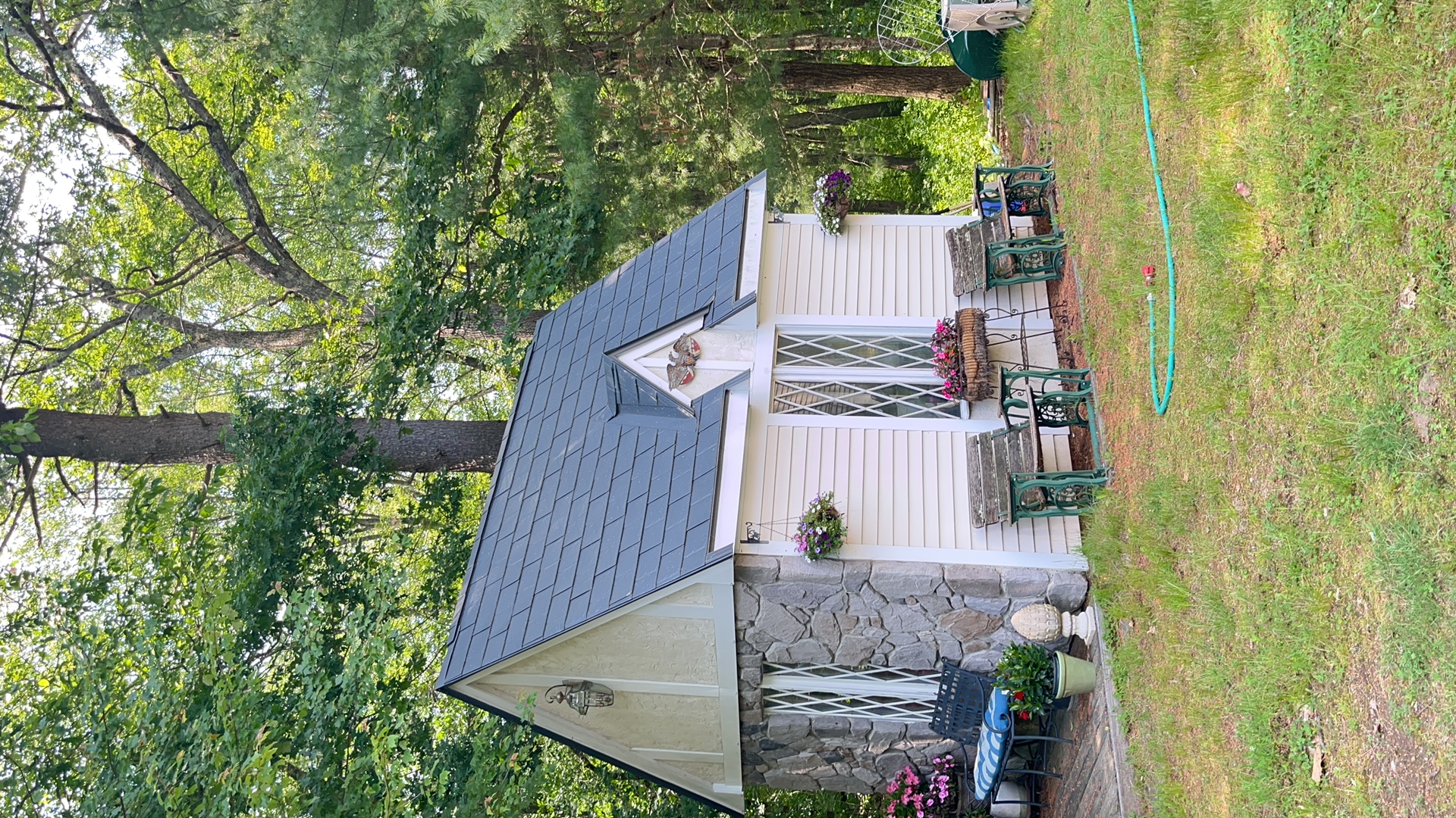 Charcoal grey Interlock aluminum slate metal roof on a storybook cottage with stone accent wall, steep gables, and a front dormer in Norfolk, MA.