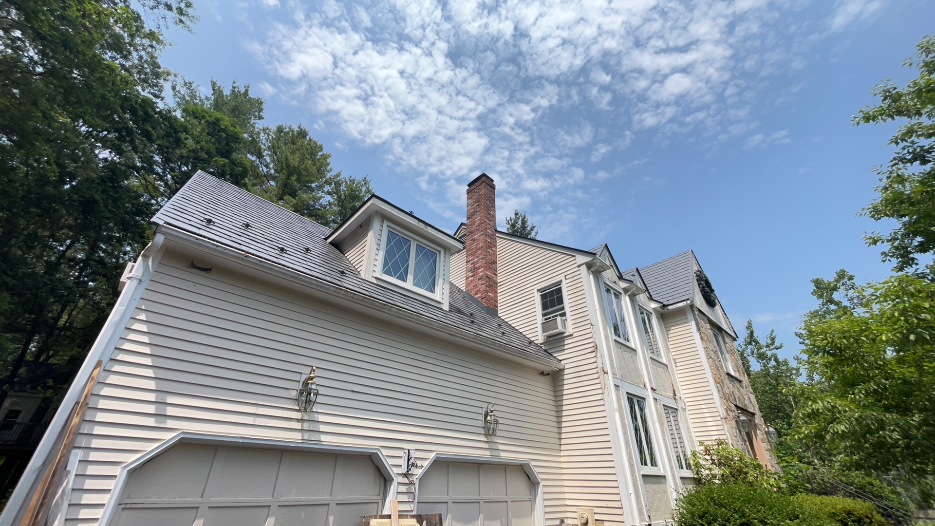 Charcoal grey Interlock aluminum slate metal roof on a 2-story Victorian home in Norfolk, MA, featuring a brick chimney and multi-plane roofline.