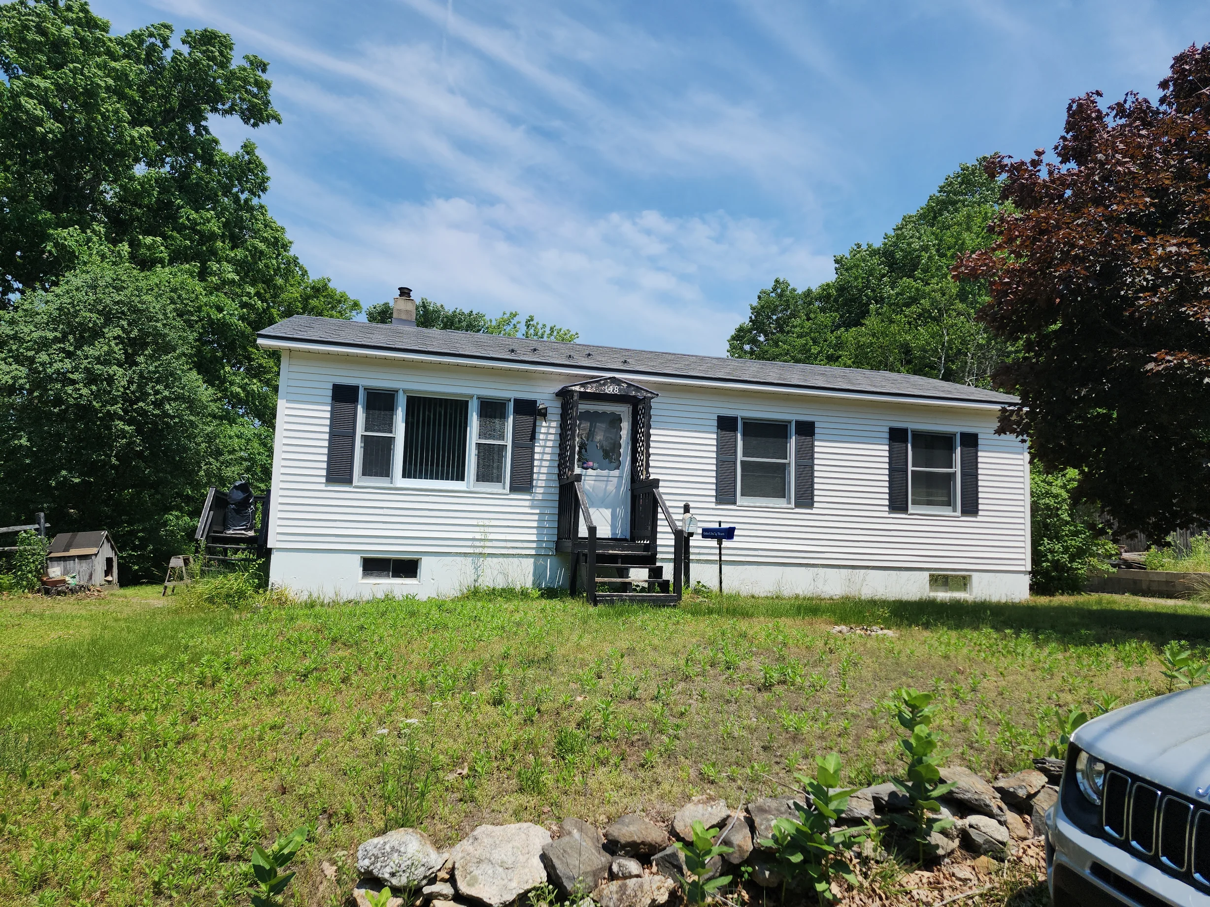 Charcoal Grey Interlock Slate aluminum roof on a white single-storey home with a metal roof in a wooded, Athol, Massachusetts