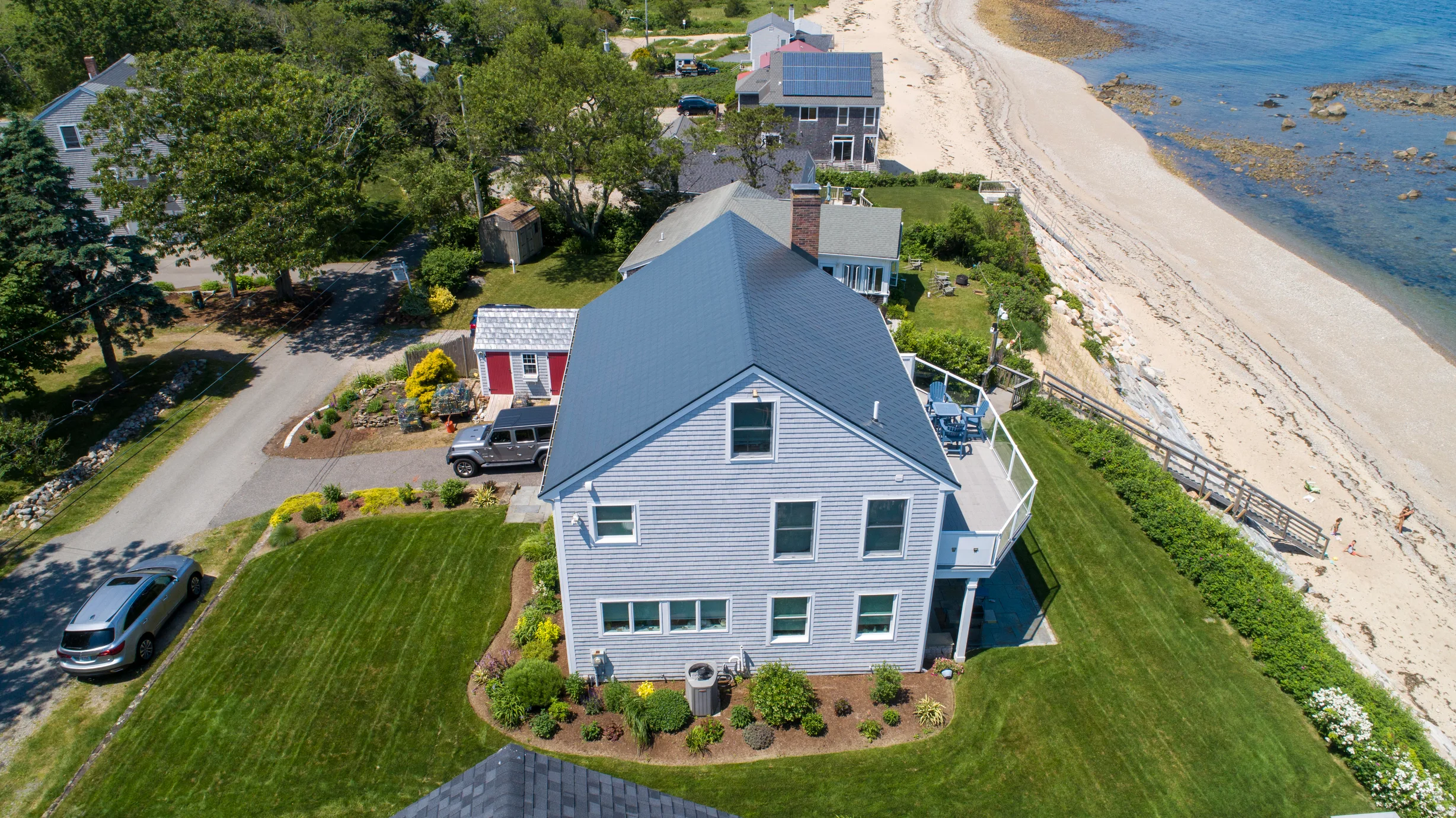 Deep Charcoal Interlock Slate aluminum roof on a white Cape Cod home on a waterfront property with lush, Plymouth, Massachusetts