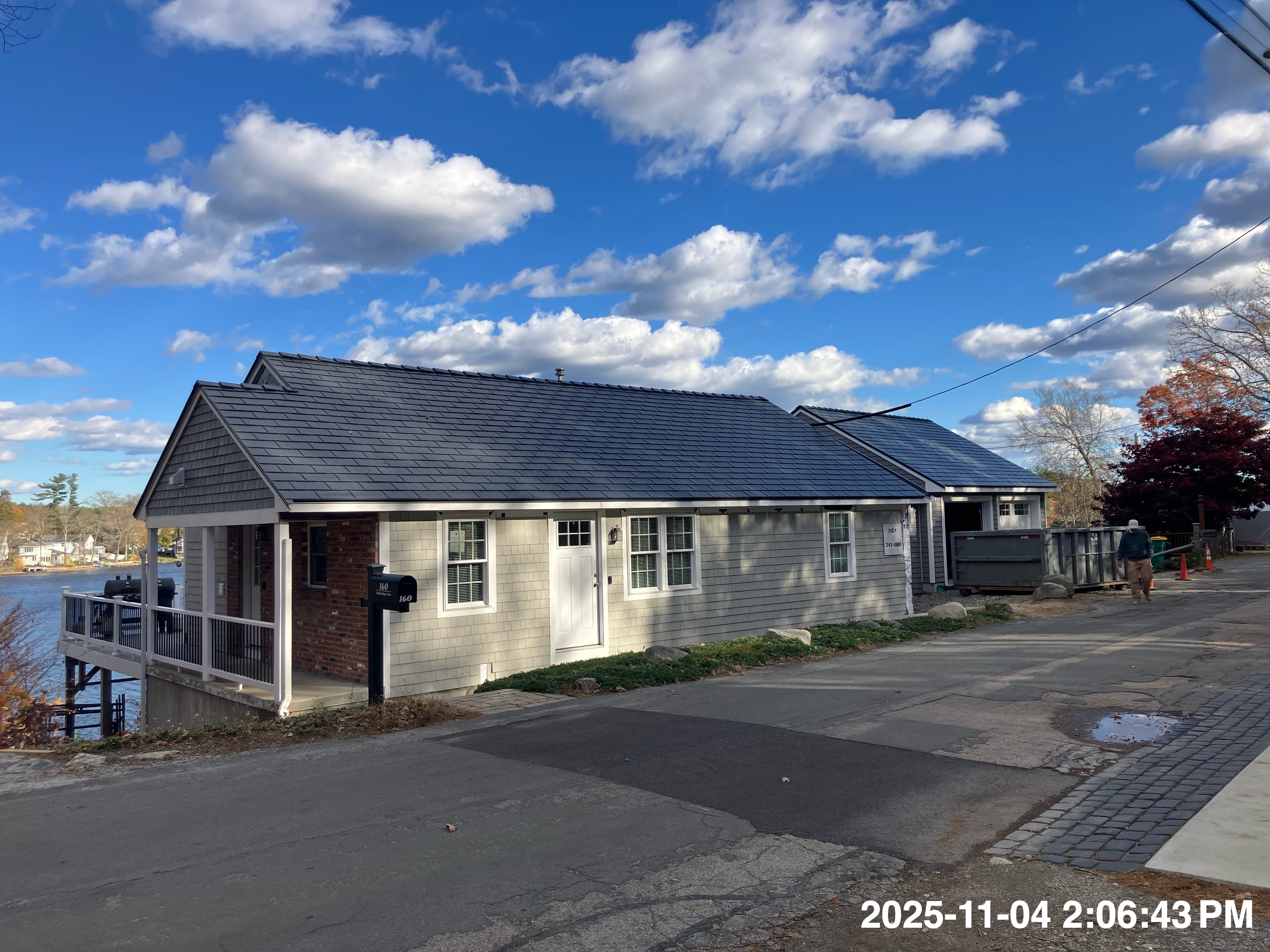 Single-story lakeside cottage with Deep Charcoal Interlock cedar shingle metal roof, gable profile, gray shingle siding, and brick accent in North Attleboro, MA.