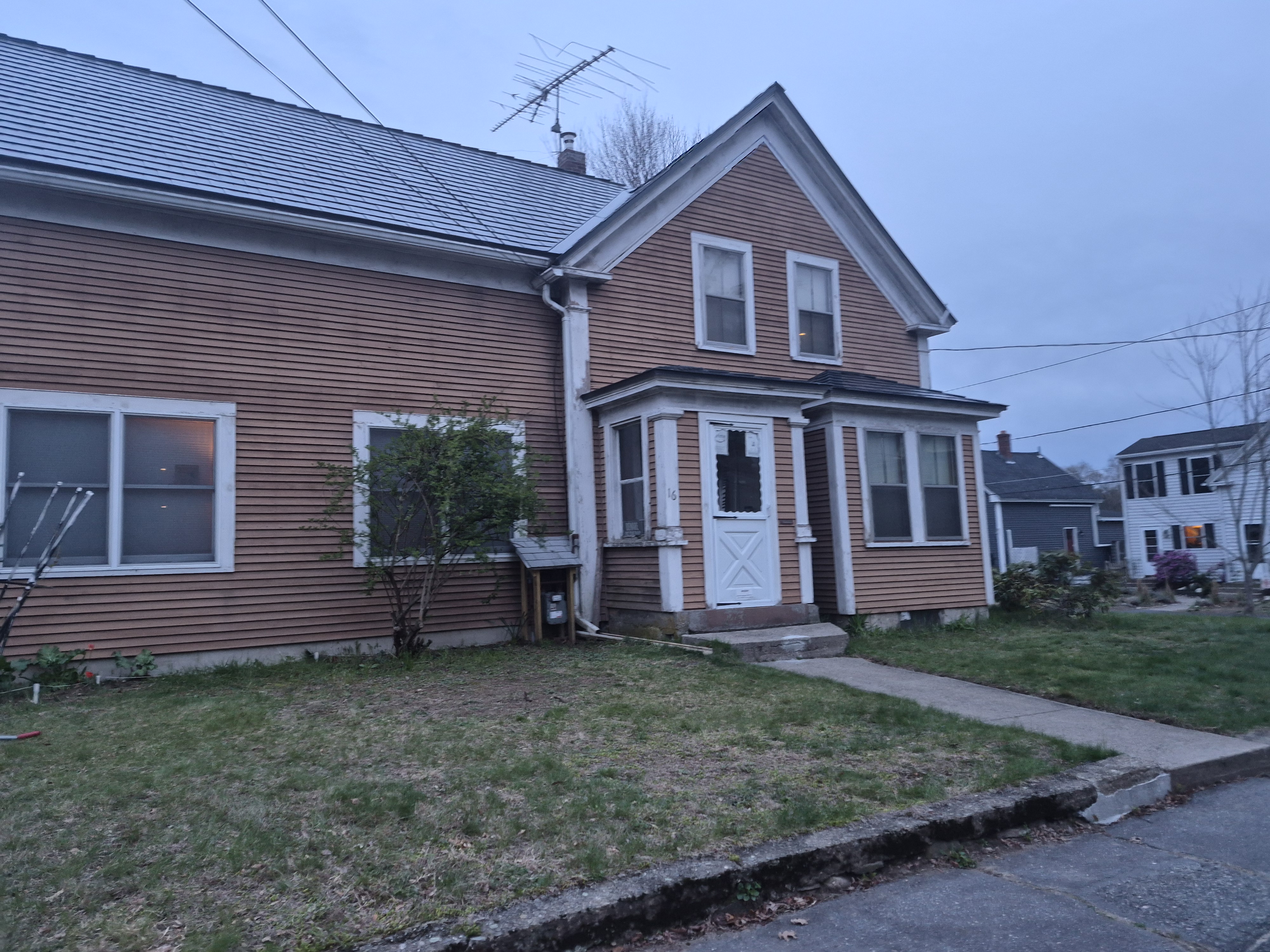 Two-story Victorian-style home in Ayer, MA with deep charcoal Interlock aluminum slate metal roofing, gable front entry, and horizontal wood siding.