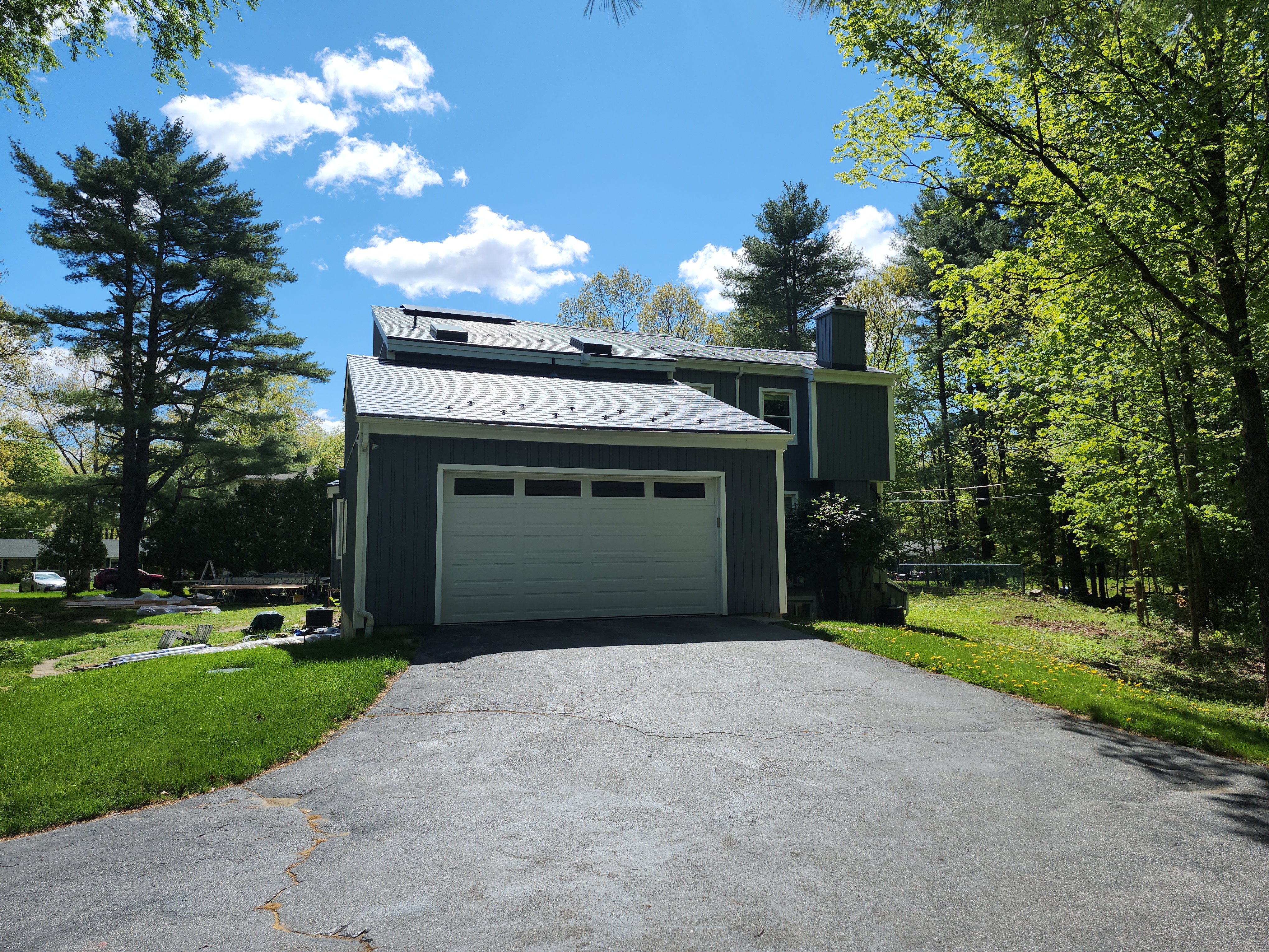 Two-story colonial home in Sturbridge MA with deep charcoal Interlock aluminum slate metal roof, attached two-car garage, chimney, and skylights amid lush trees.