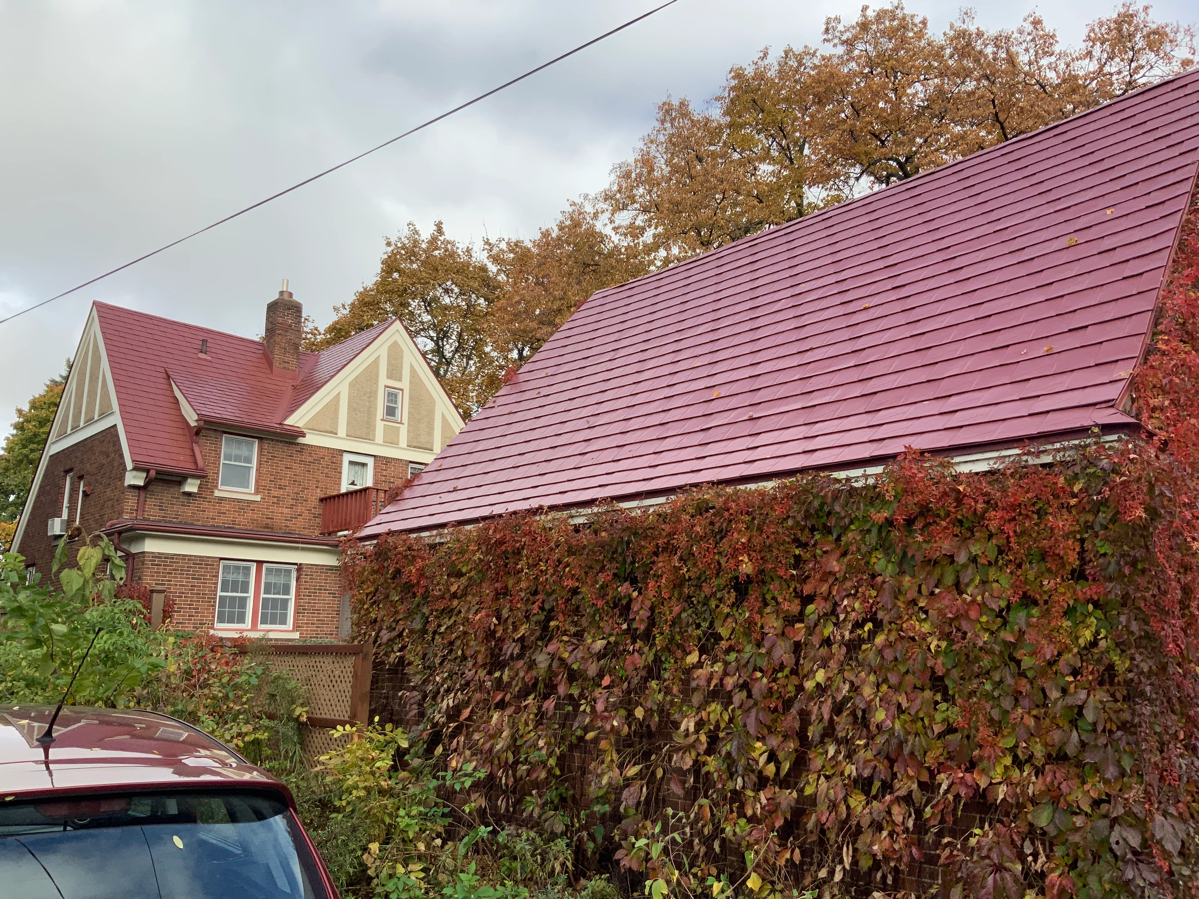 Tile Red Interlock Tile aluminum roof on a brick colonial home with red metal roof among trees, Saint Paul, Minnesota