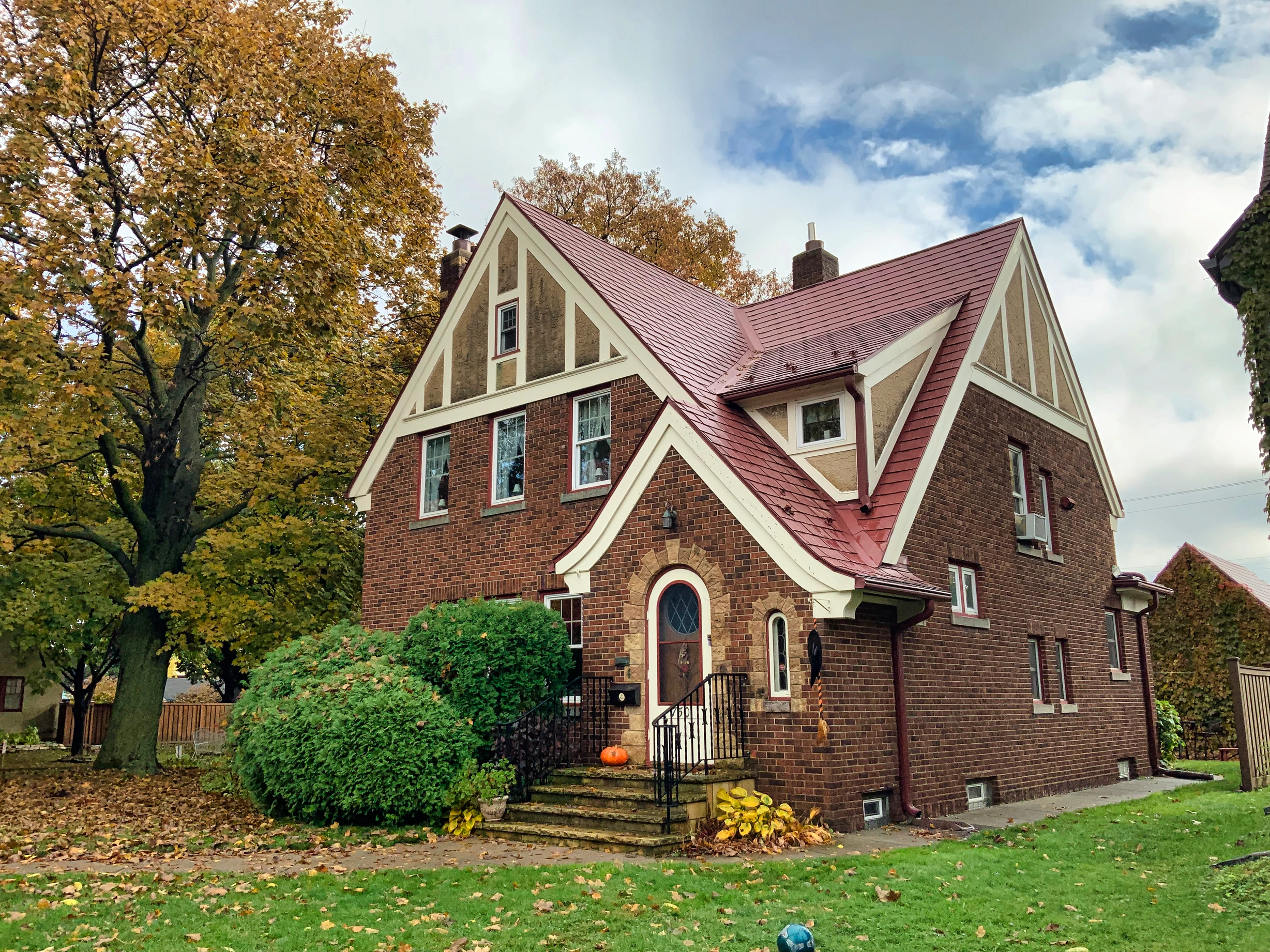 Tile Red Interlock Tile aluminum roof on a brick two-storey home with dormers among tall trees, Saint Paul, Minnesota