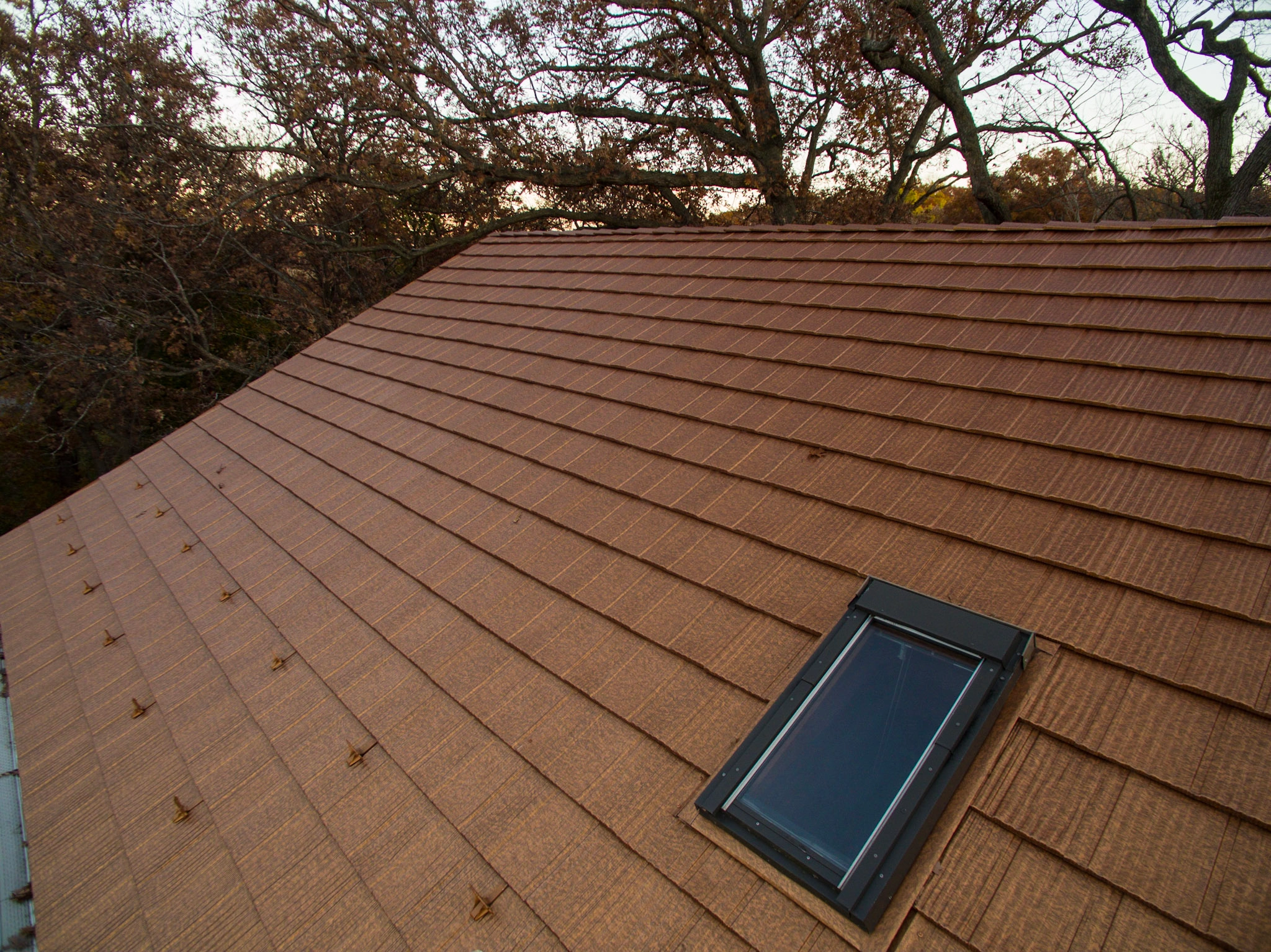 Aged Copper Interlock Shake aluminum roof on a two-storey home with an aged copper metal roof among tall, Bloomington, Minnesota
