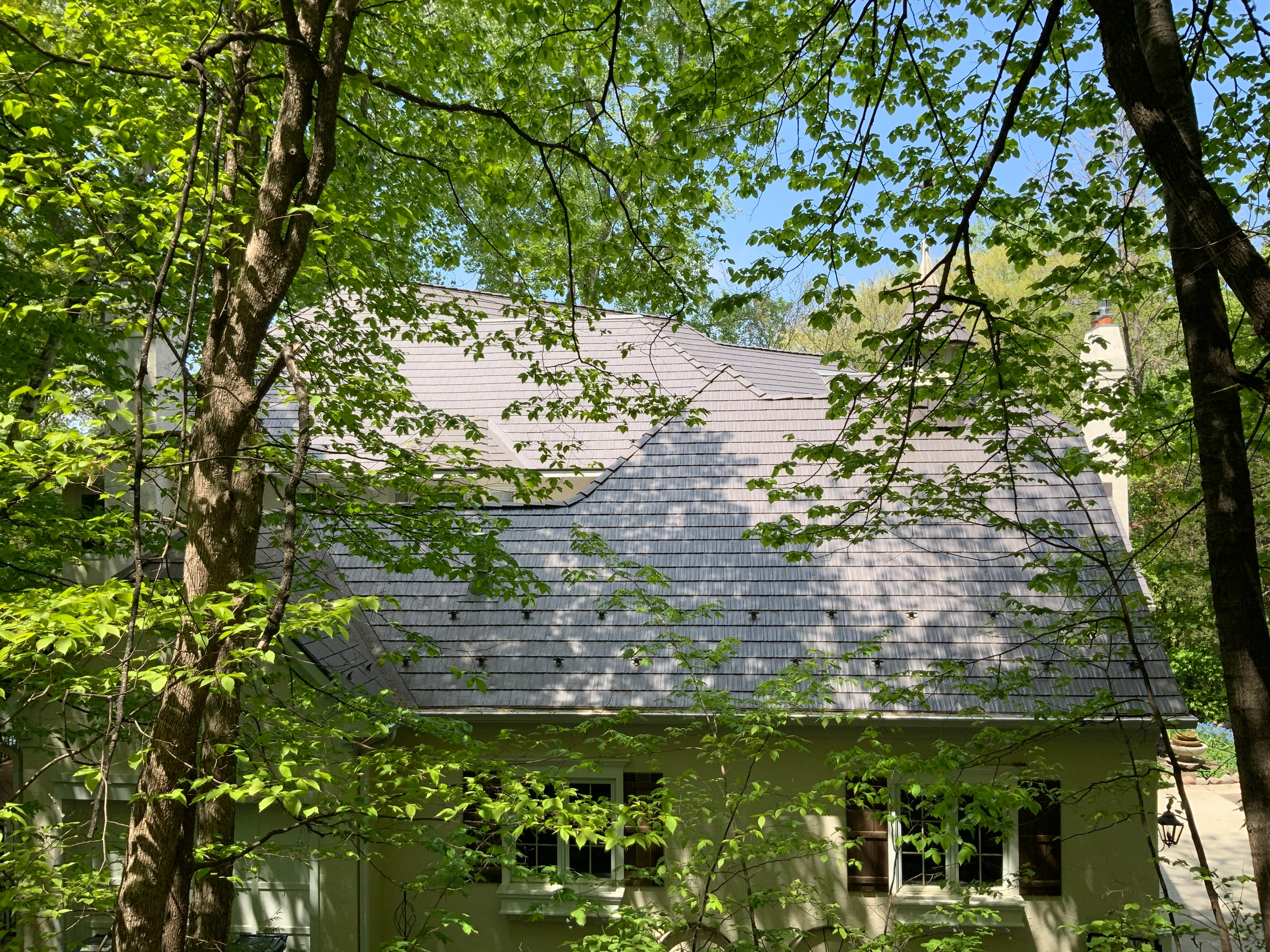 Weathered Interlock Cedar Shingle aluminum roof on a two-storey home with dormers in a forest, Shorewood, Minnesota