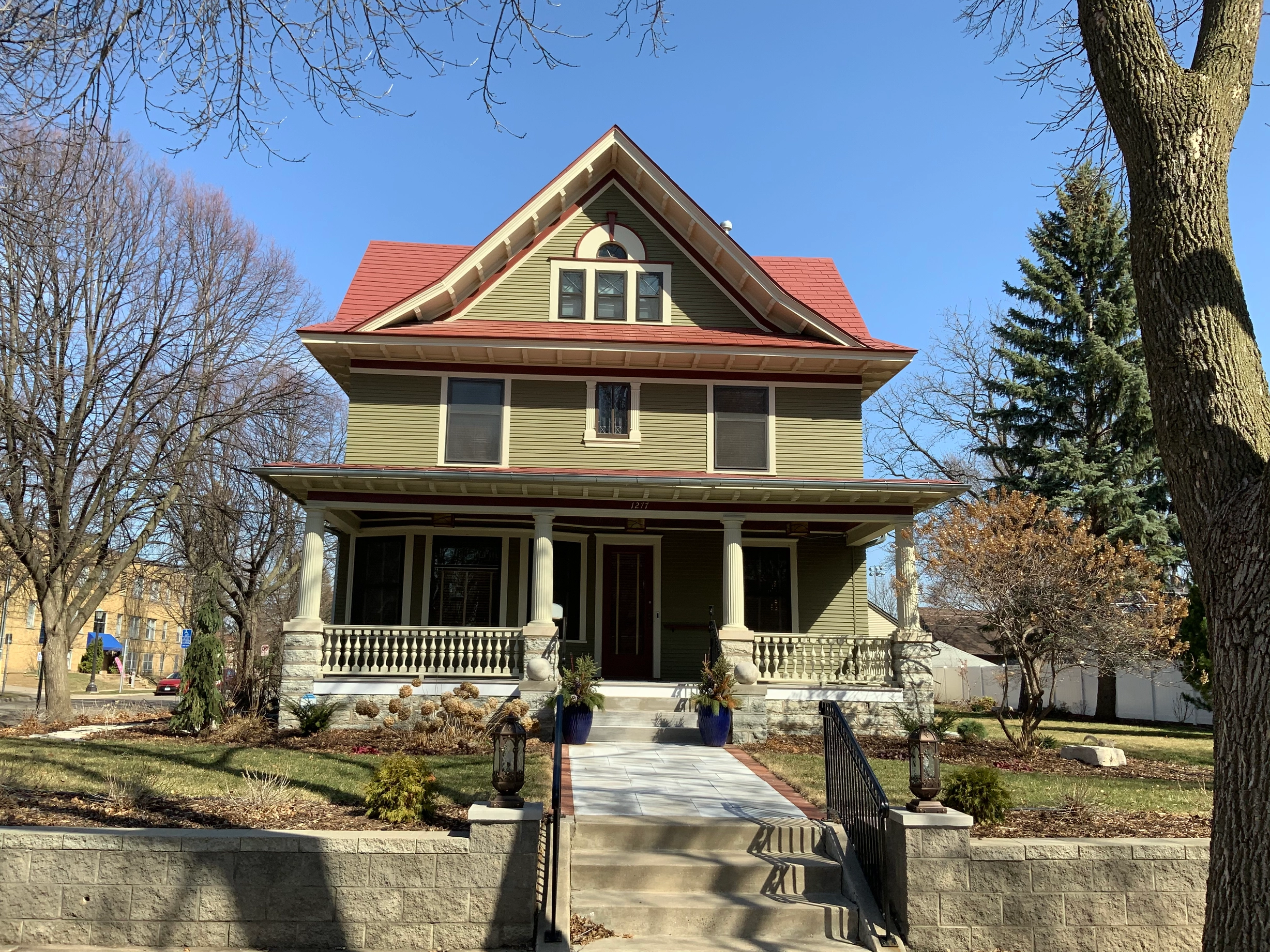 Tile Red Interlock Slate aluminum roof on a two-storey home with dormers among tall trees, St. Paul, Minnesota