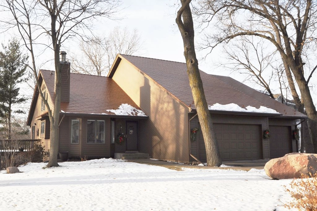 Aged Copper Interlock Cedar Shingle aluminum roof on a brown ranch-style home with a garage among trees in snow, Burnsville, Minnesota