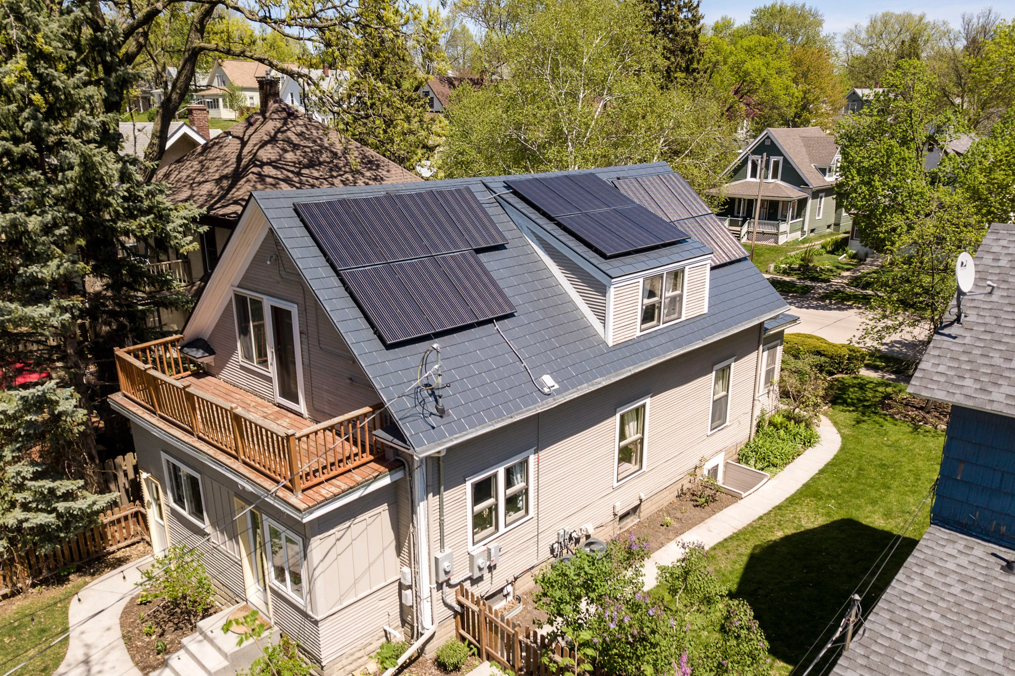Deep Charcoal Interlock Slate aluminum roof on a cream coloured two-storey home with dormers among tall, Minneapolis, Minnesota