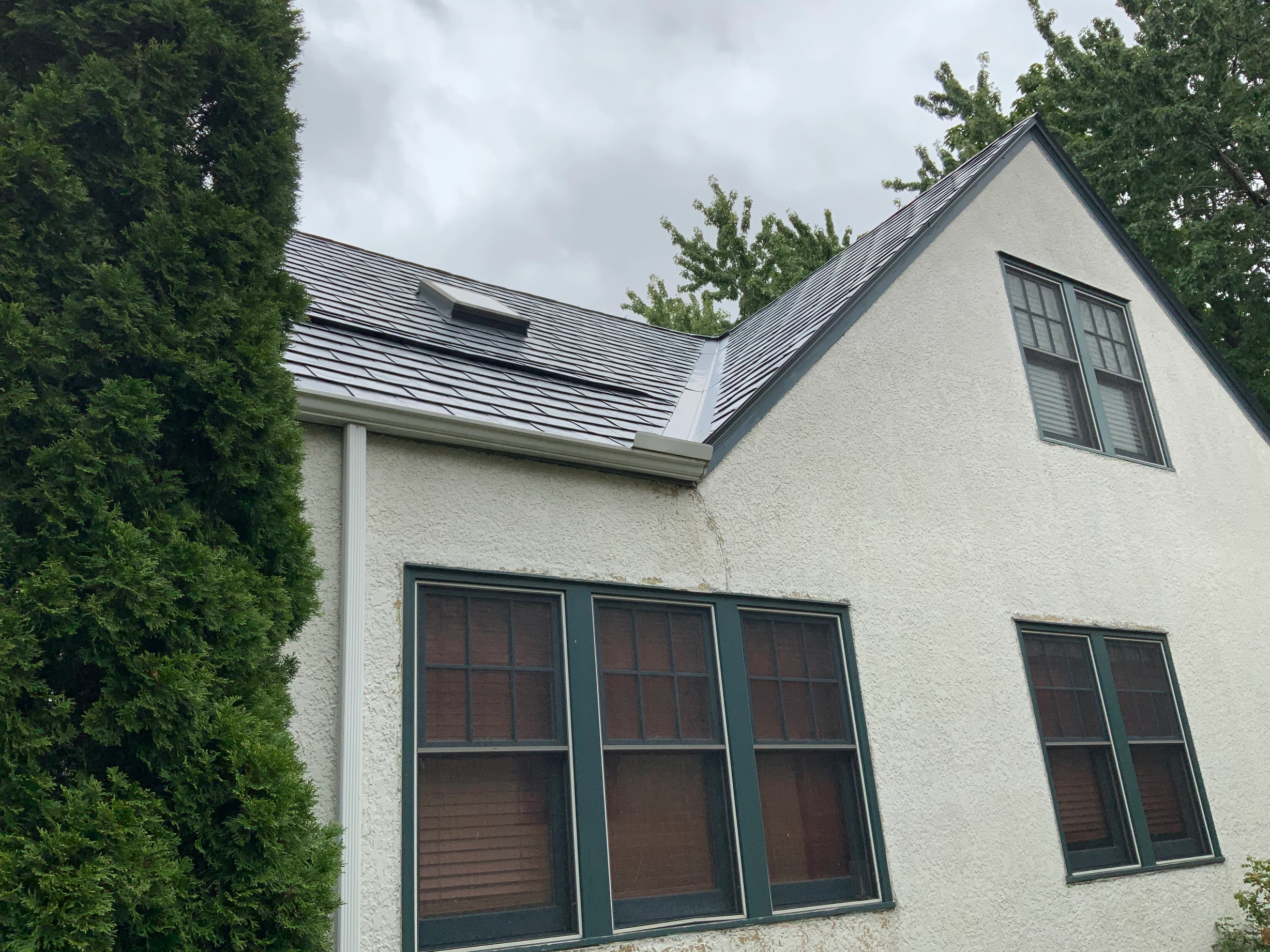 Deep Charcoal Interlock Slate aluminum roof on a white two-storey colonial home with dormers in a forested, Saint Paul, Minnesota