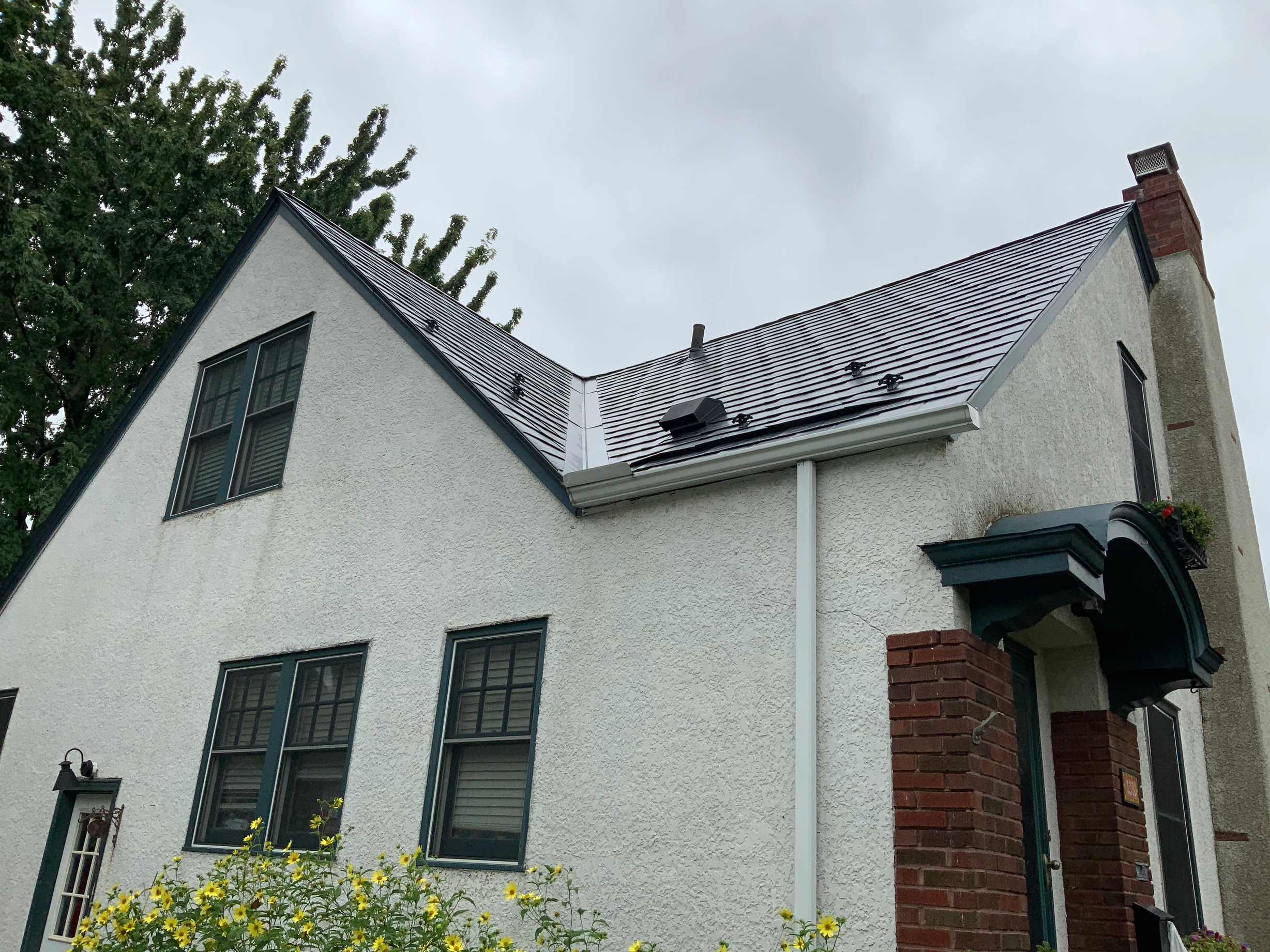 Deep Charcoal Interlock Slate aluminum roof on a white Colonial home with dormers among tall trees, Saint Paul, Minnesota