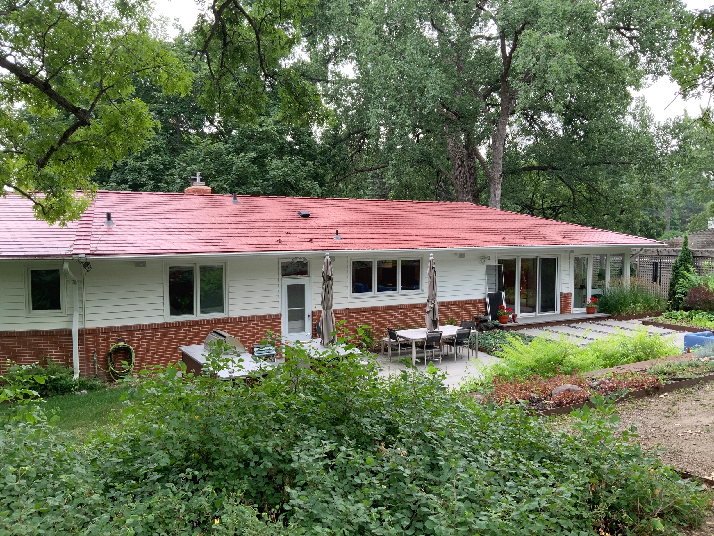 Tile Red Interlock Slate aluminum roof on a red roofed ranch house with patio among tall trees, Edina, Minnesota