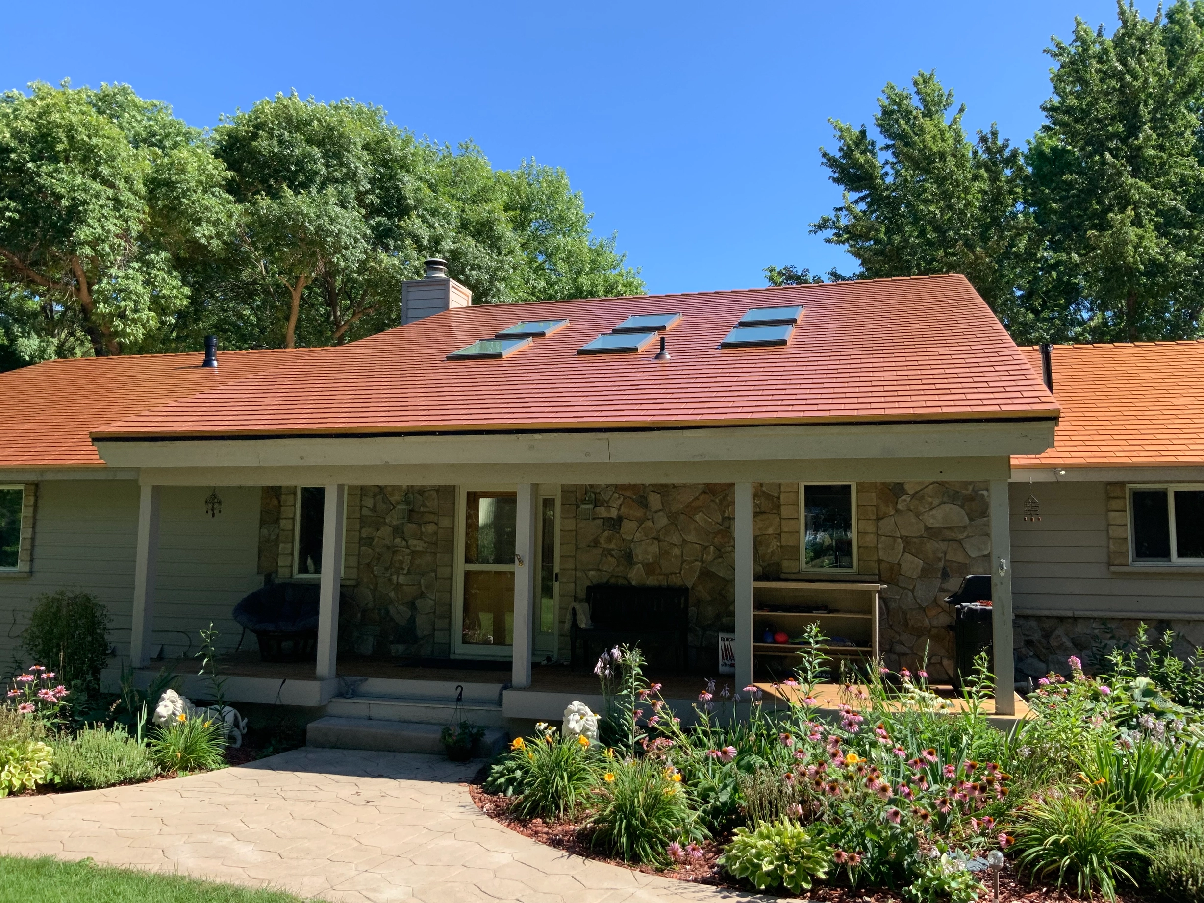Copper Penny Interlock Slate aluminum roof on a beige ranch style home with stone facade in a wooded, Shorewood, Minnesota