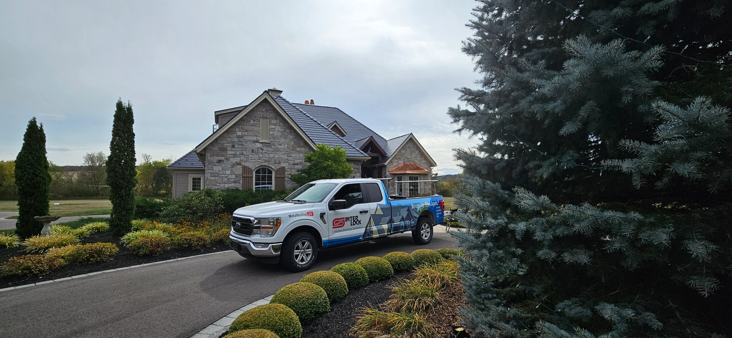 Deep Charcoal Interlock Slate aluminum roof on a stone house with dormers in a rural suburban setting, Sussex, New Brunswick
