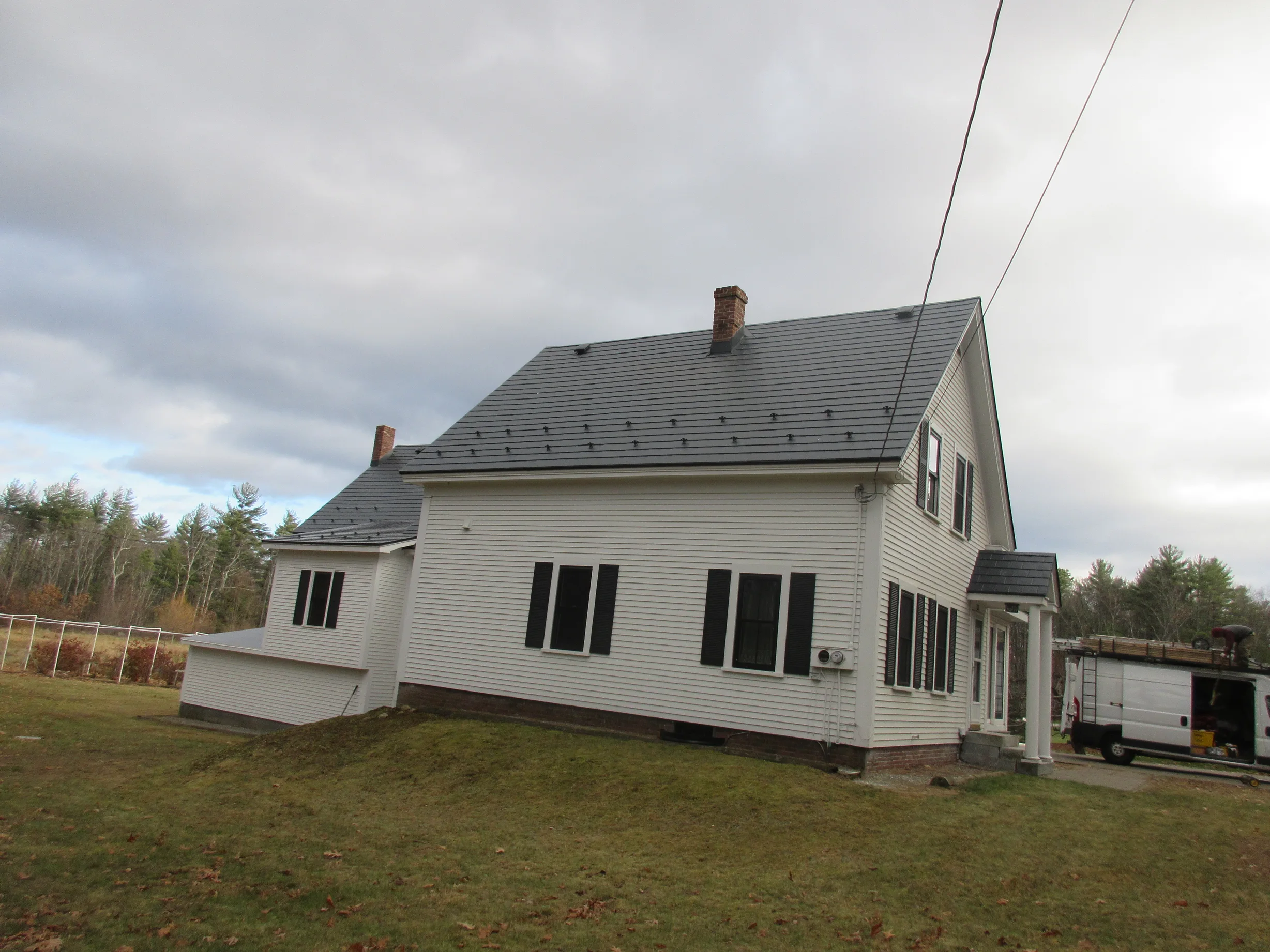 Deep Charcoal Interlock Slate aluminum roof on a white colonial home with dormers on a forested lot, Merrimack, New Hampshire