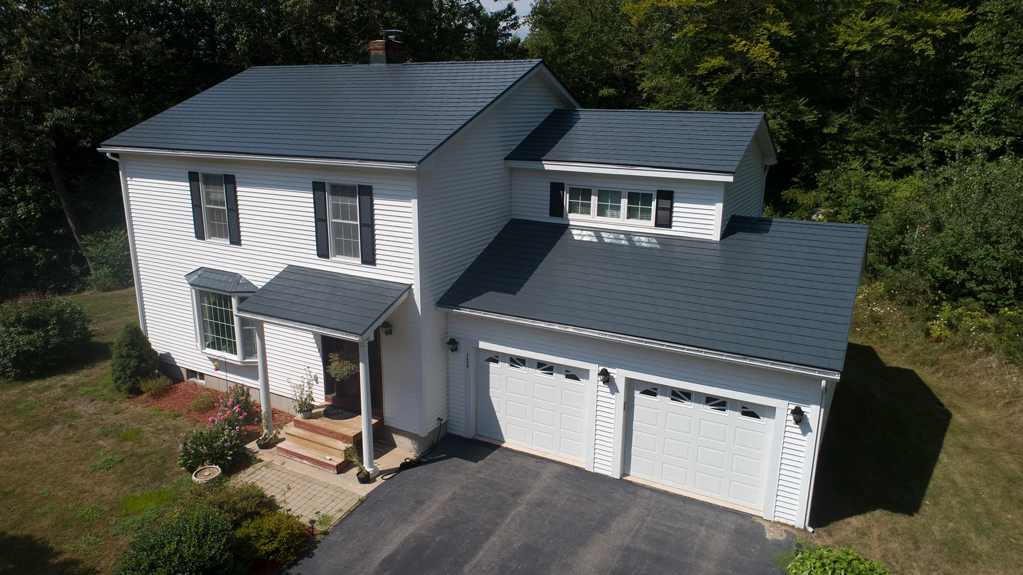 Charcoal Grey Interlock Slate aluminum roof on a white two-storey Colonial home among tall green trees, Webster, New Hampshire