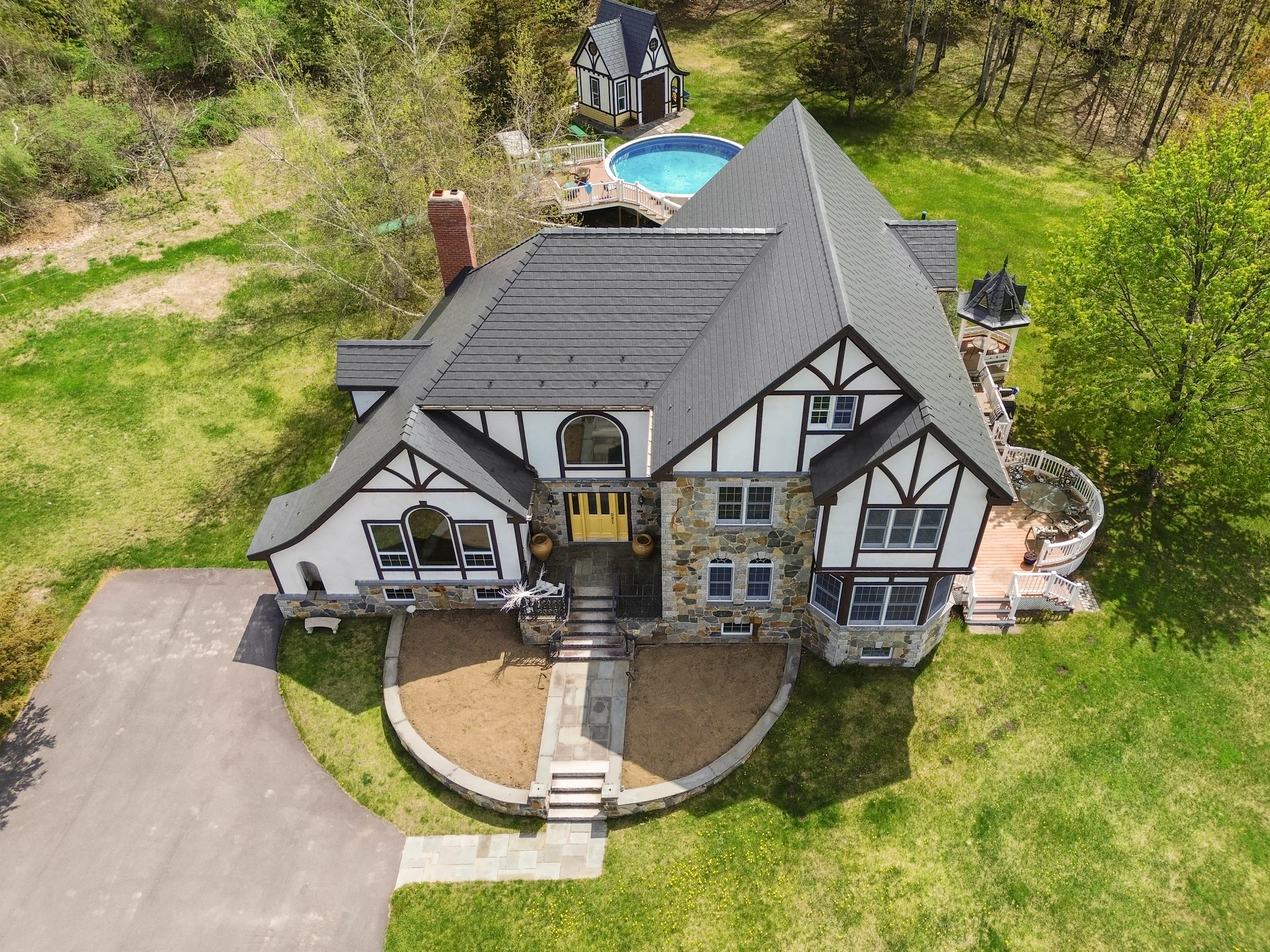 Deep Charcoal Interlock Slate aluminum roof on a two-storey Tudor home among trees in a forested area, Madbury, New Hampshire