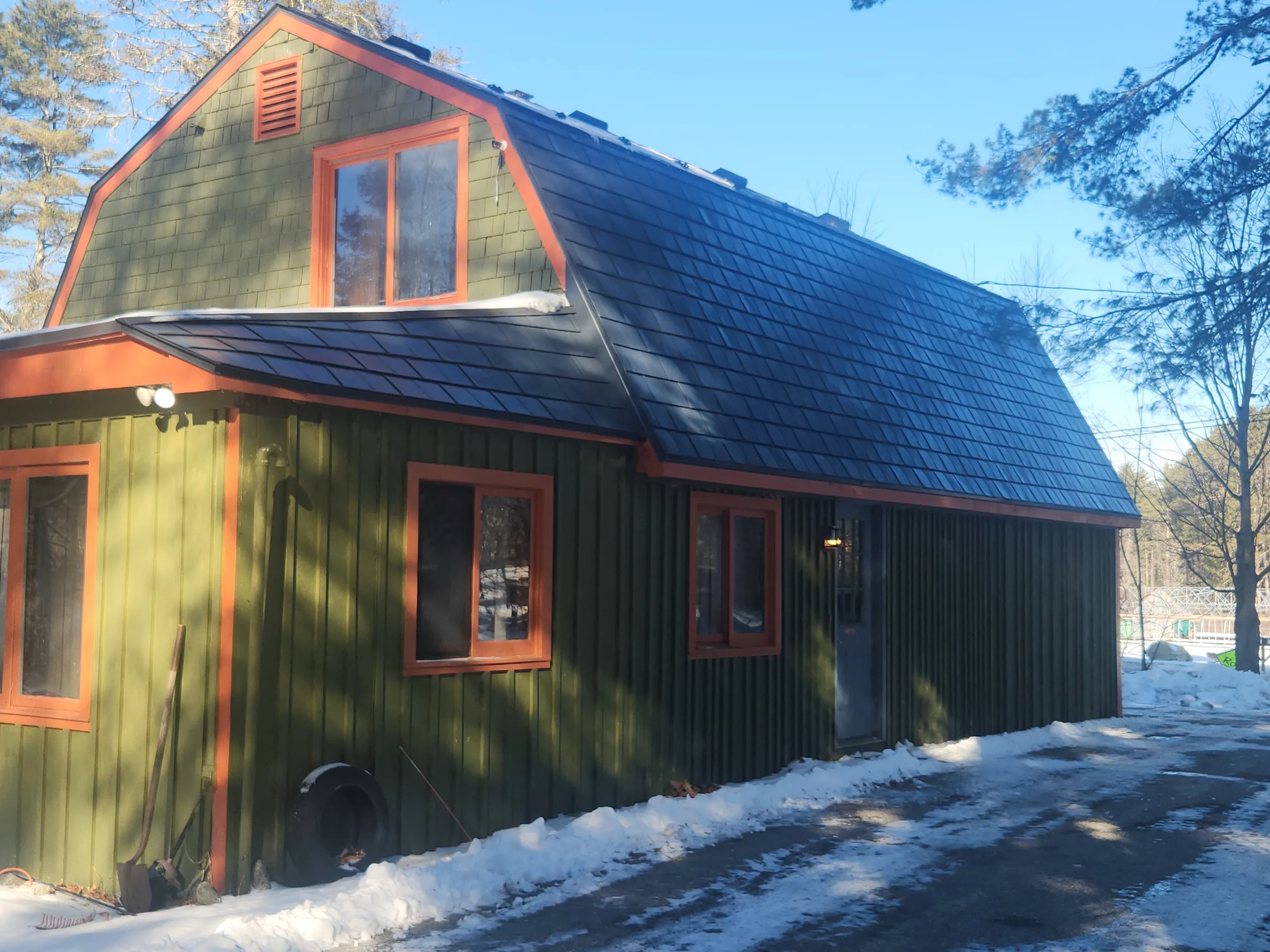 Deep Charcoal Interlock Slate aluminum roof on a green home with a black roof among tall trees, Wilmot, New Hampshire