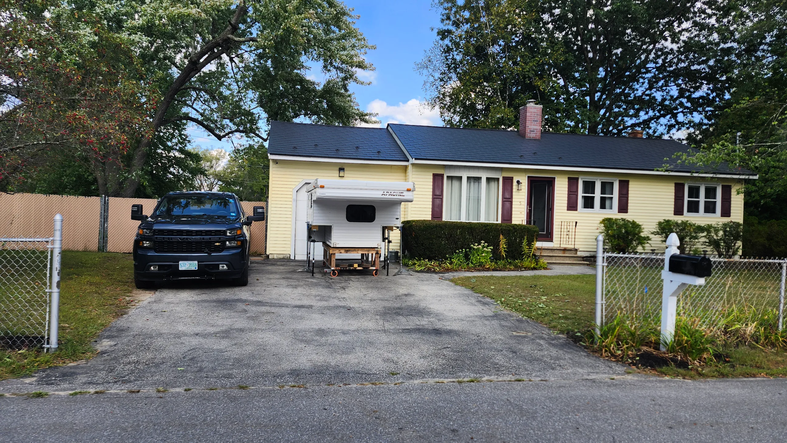 Single-story ranch home in Bedford, NH featuring a new black Interlock aluminum slate metal roof with dark gable profile and brick chimney.